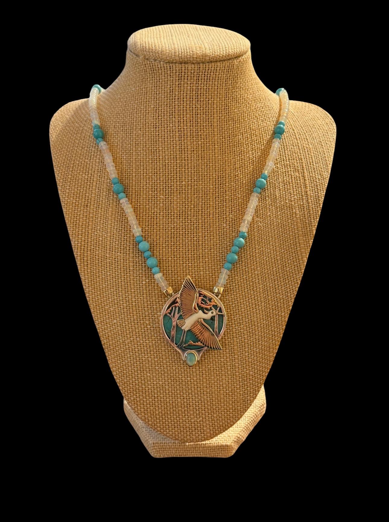     Vollständig handgefertigtes Stück. Handgefertigt. Handgeschnitzter Anhänger aus Howlite, 9-karätigem Gelbgold und Sterlingsilber mit einem weißen Reiher in Lünettenfassung
7 mm x 5 mm x 5 mm großer Opal-Cabochon, umgeben von einer
