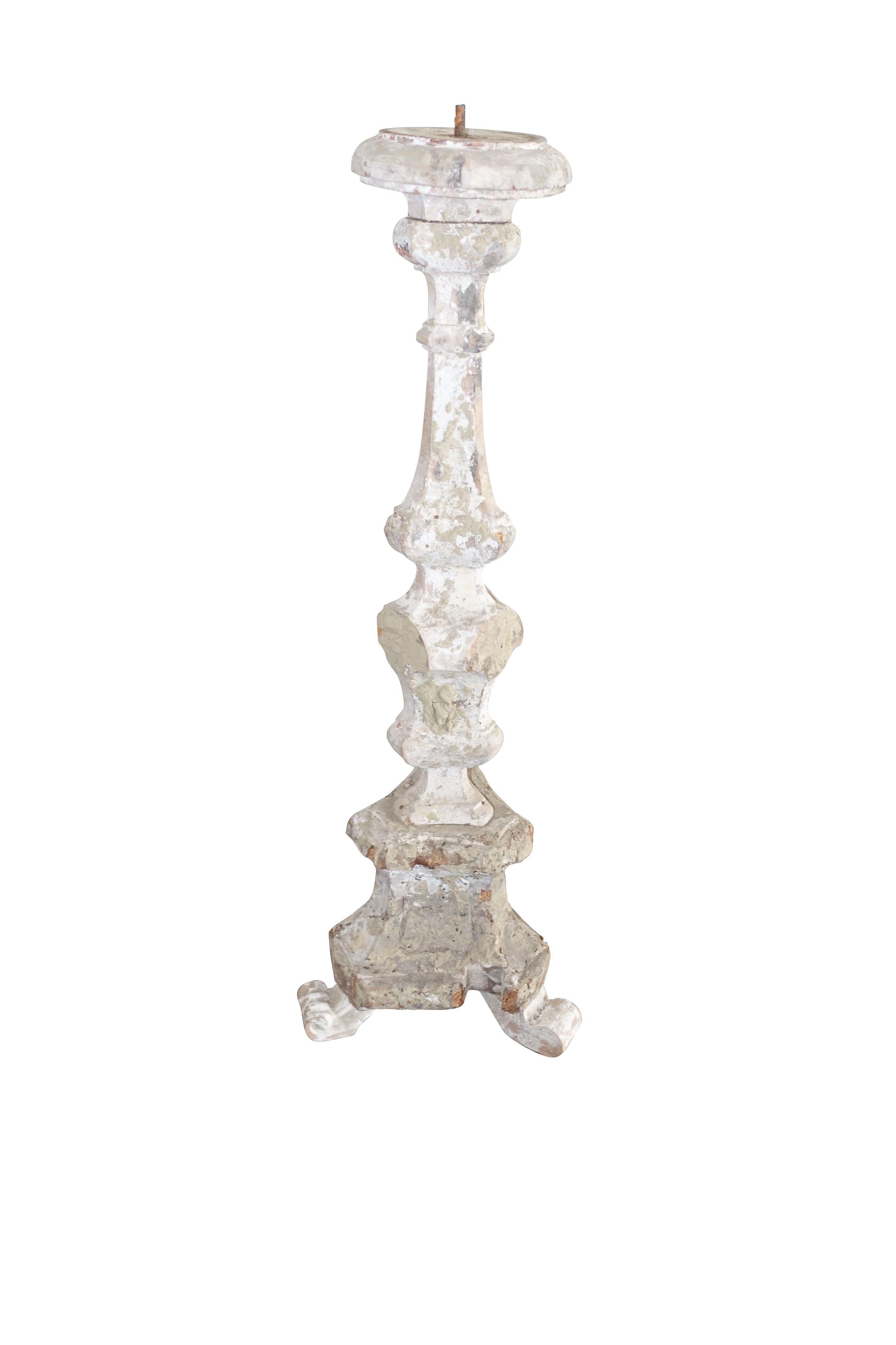 19th century Italian wooden hand carved candlestick originally housed on alters in cathedrals.
Originally painted white, the candlesticks now have a natural weathered patina. 
Three footed with two facing forward more decorative, as was the custom