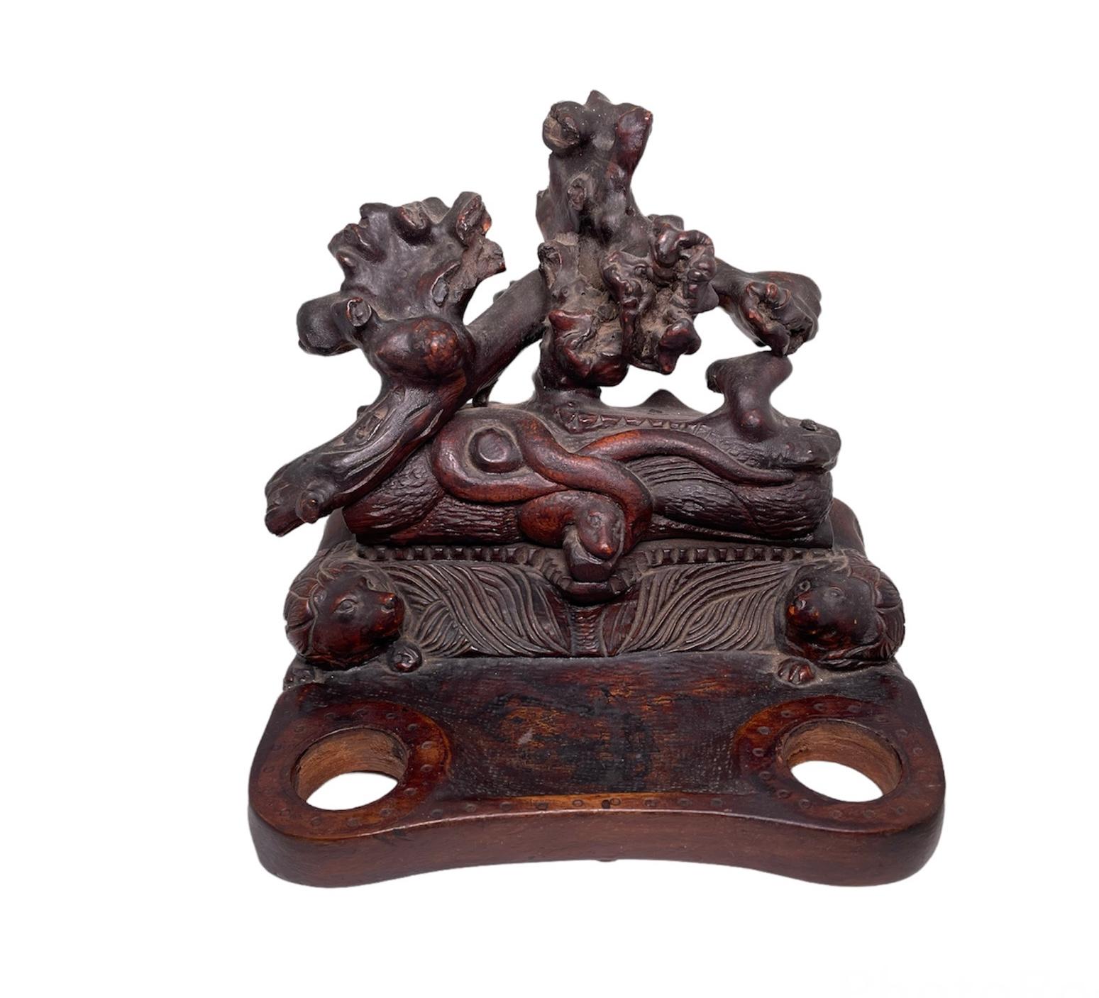 This is a hand carved wood double inkwells with two glass jars. Its base is almost square shaped. Over this base there are two large lions with a lot of hair laying down at each side and looking up to a snake that is coiled around a wood trunk that