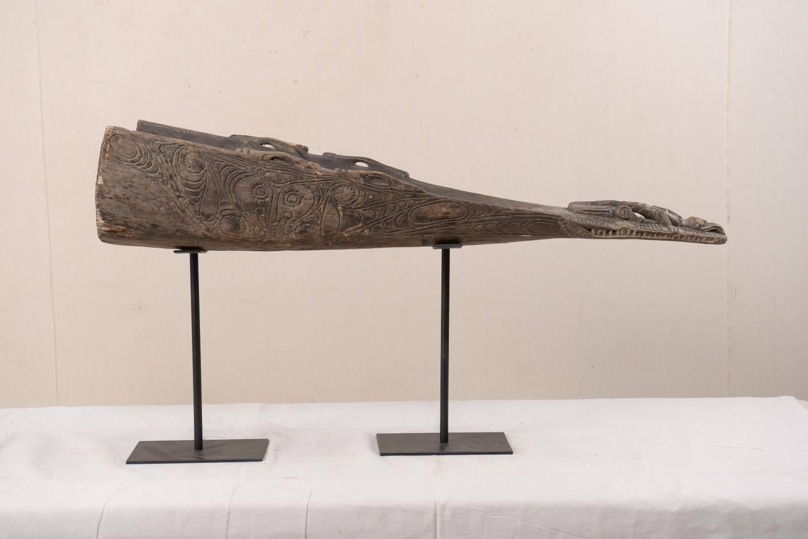 A carved wood crocodile head boat prow from Papua New Guinea. This mid-20th century Papua New Guinean boat prow has been carved out of wood and features the head of a crocodile. This boat prow is displayed and supported on two custom black iron