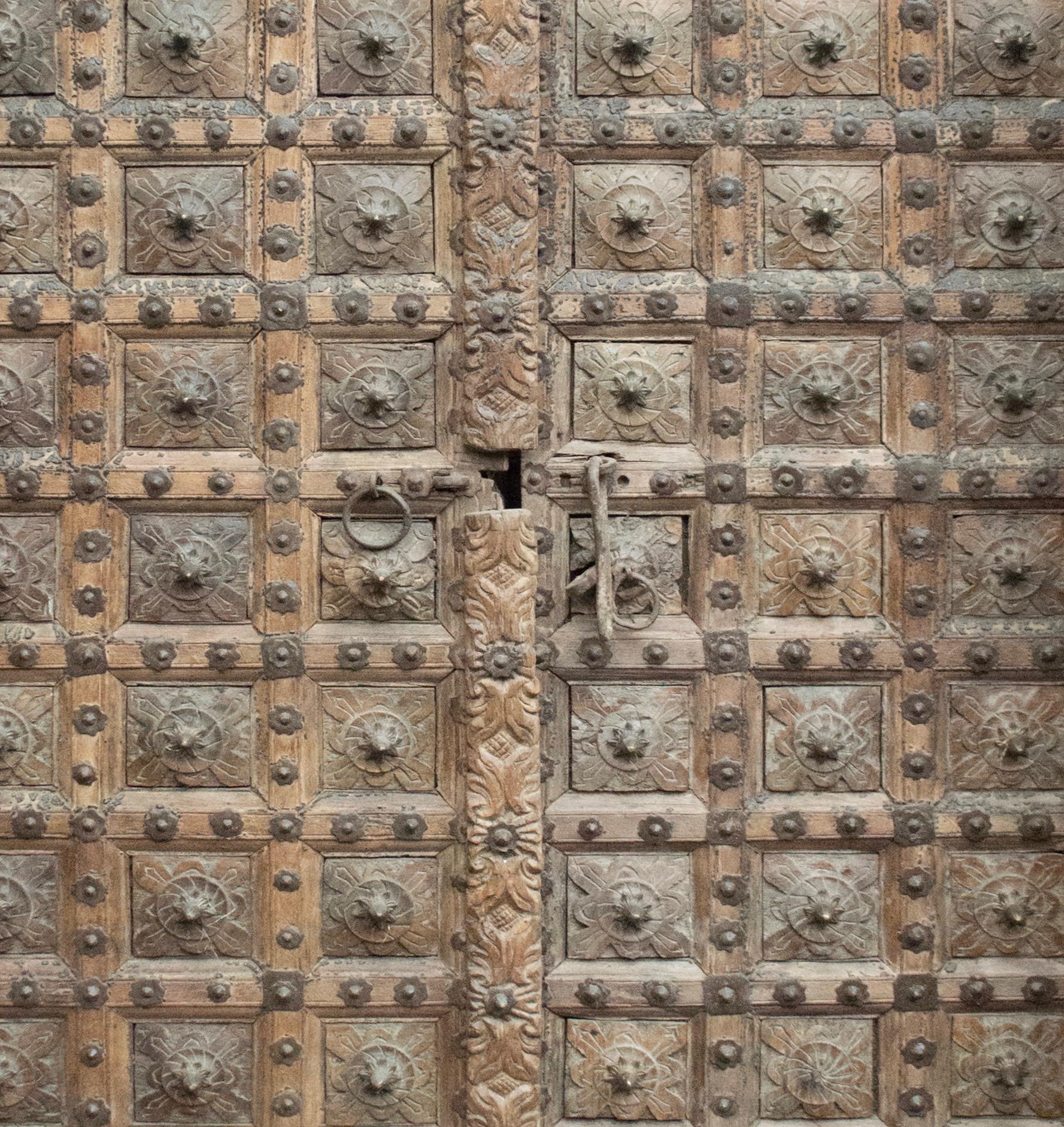 18th century two leaf door, original of the western coastal city of Gujarat, India. Made of hand carved wood, the frames as the door are beautifully decorated in sequences of organic motifs with metal tips.