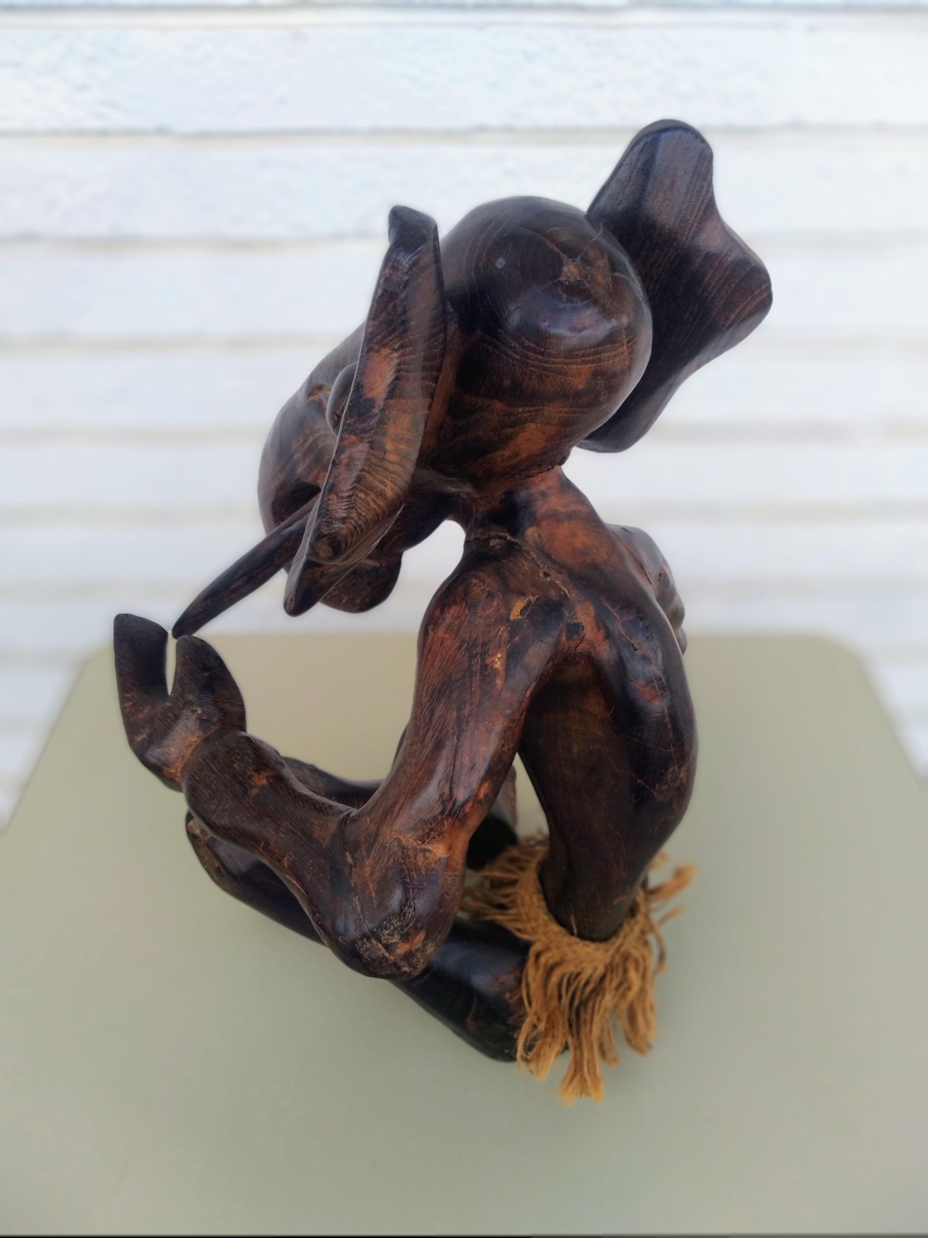 Il s'agit d'une magnifique sculpture. Elle représente un animal mi-homme, mi-éléphant... Il possède une jupe en toile de jute tressée autour de la taille. 

C'est une œuvre d'art joliment rendue.