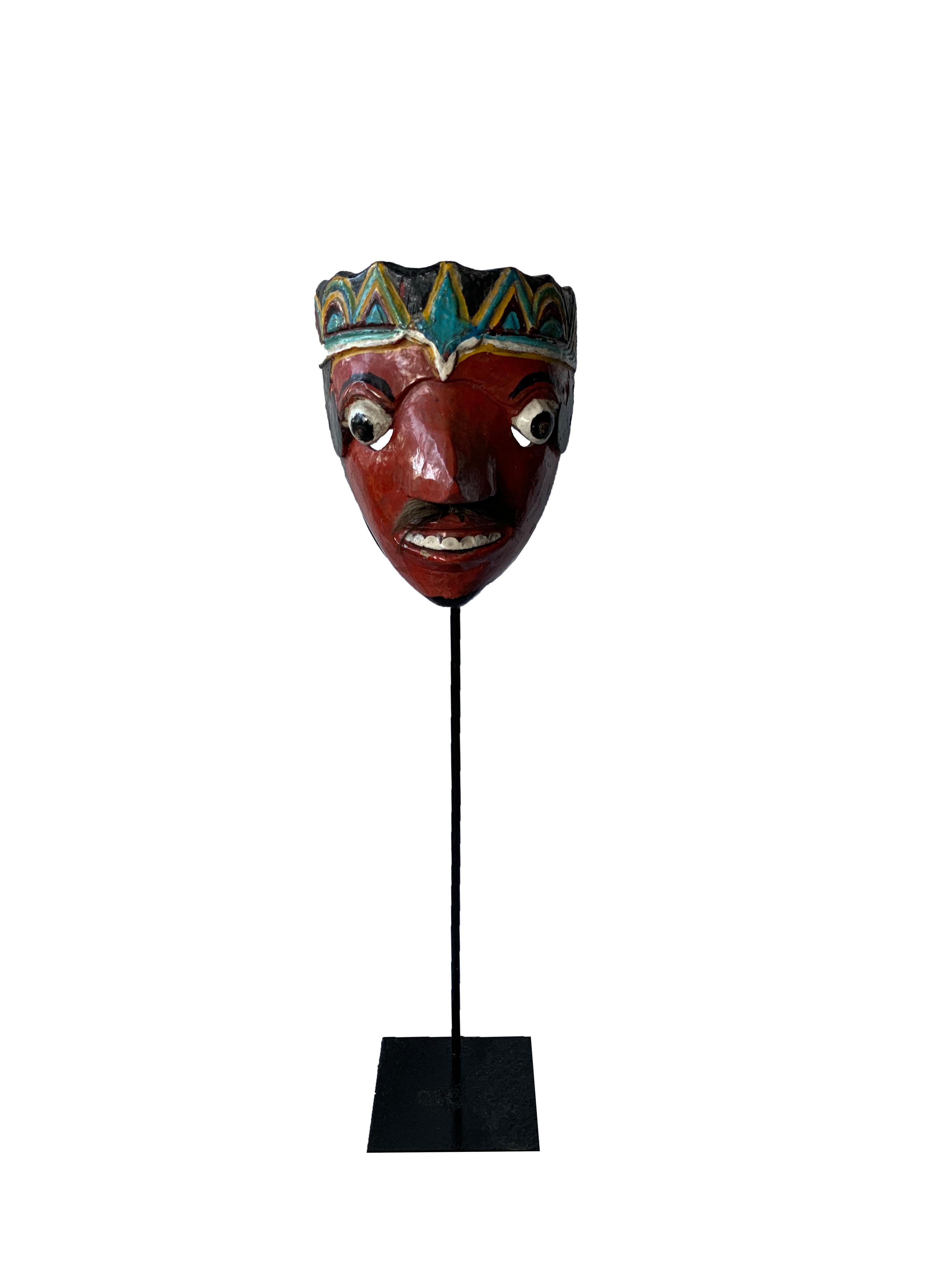 This mid-20th century ‘Wayang topeng’ mask was used in Javanese masked dance performances. This mask features a bright mix of red, yellow, white & blue polychrome. There is also a moustache using 
