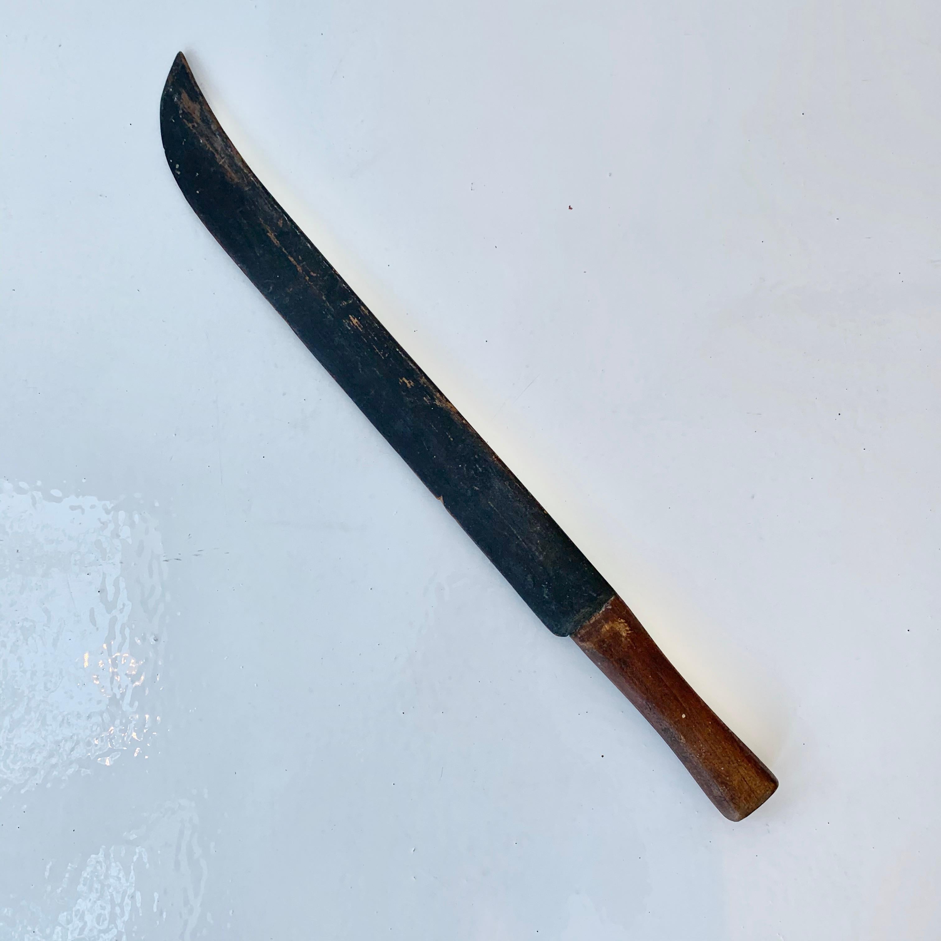 Unusual hand carved wood machete. Just under 2 feet in length. Brown handle with blackened blade. Wear and age to wood. Great tabletop object.
  