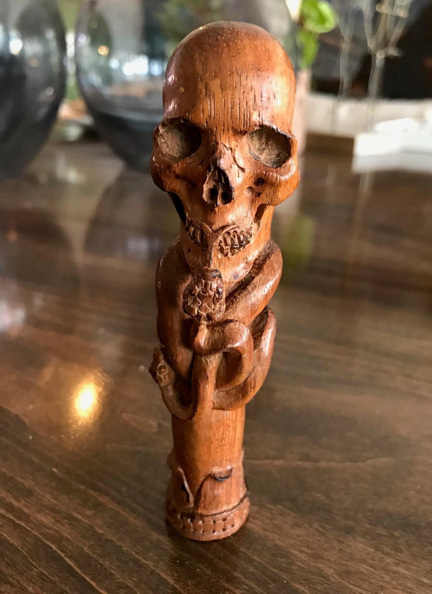 A fantastic and wonderfully hand carved piece. This smiling, mischievous skull with kissing snake is carved in very fine detail. Would be the crown jewel of any walking stick collection once attached to the cane. Truly a unique and one of a kind