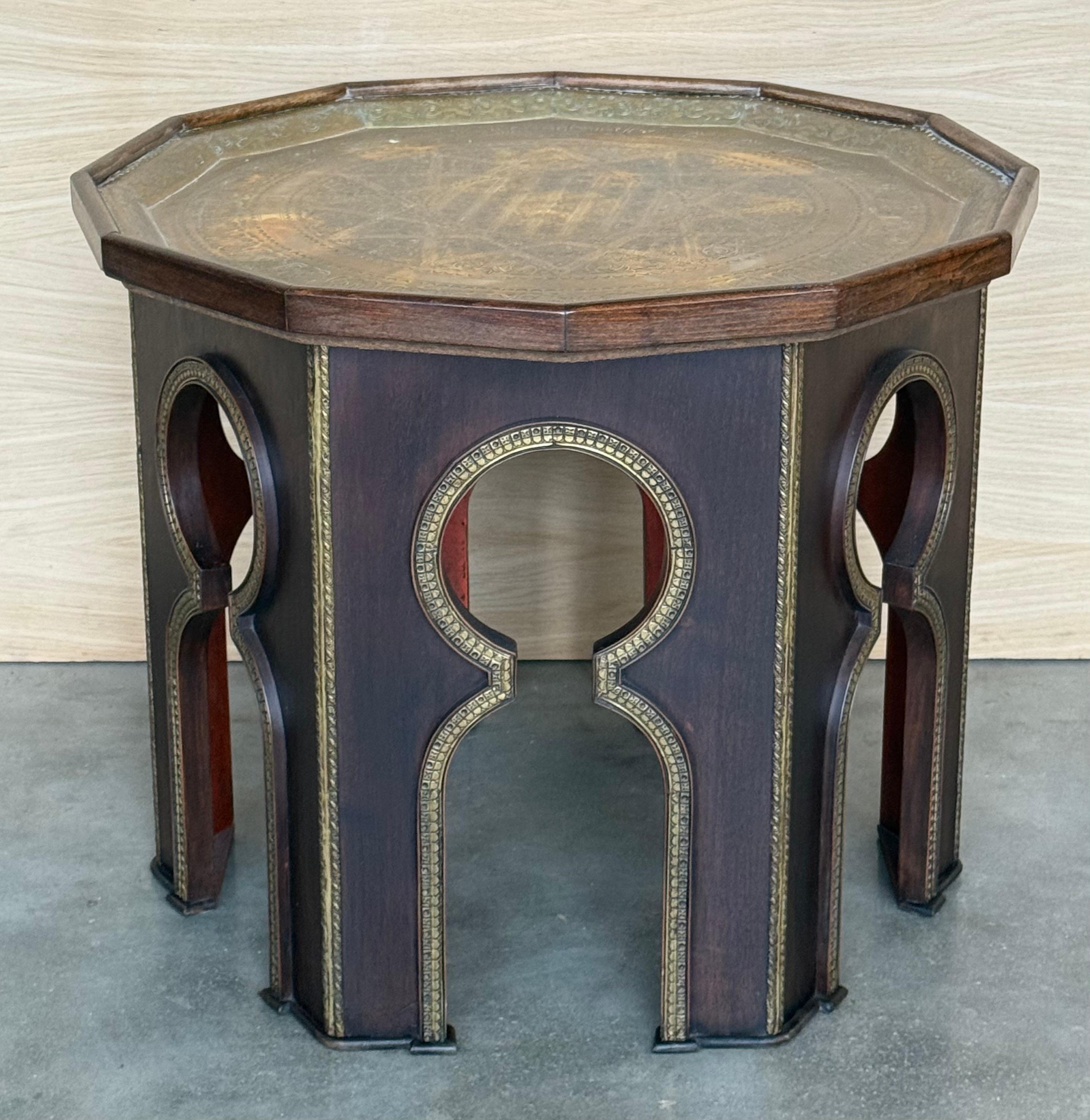 Table d'appoint marocaine ayant un plateau octogonal en métal repoussé, base sculptée avec des motifs géométriques typiques de cette zone.