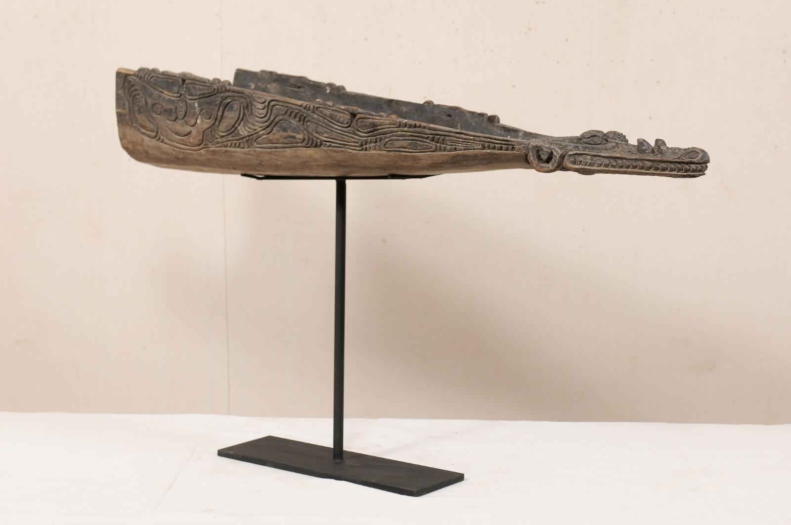 A vintage carved wood crocodile head boat prow from Papua New Guinea. This mid-20th century Papua New Guinean boat prow has been carved out of wood and features the head of a crocodile. This boat prow is displayed and supported on a custom black