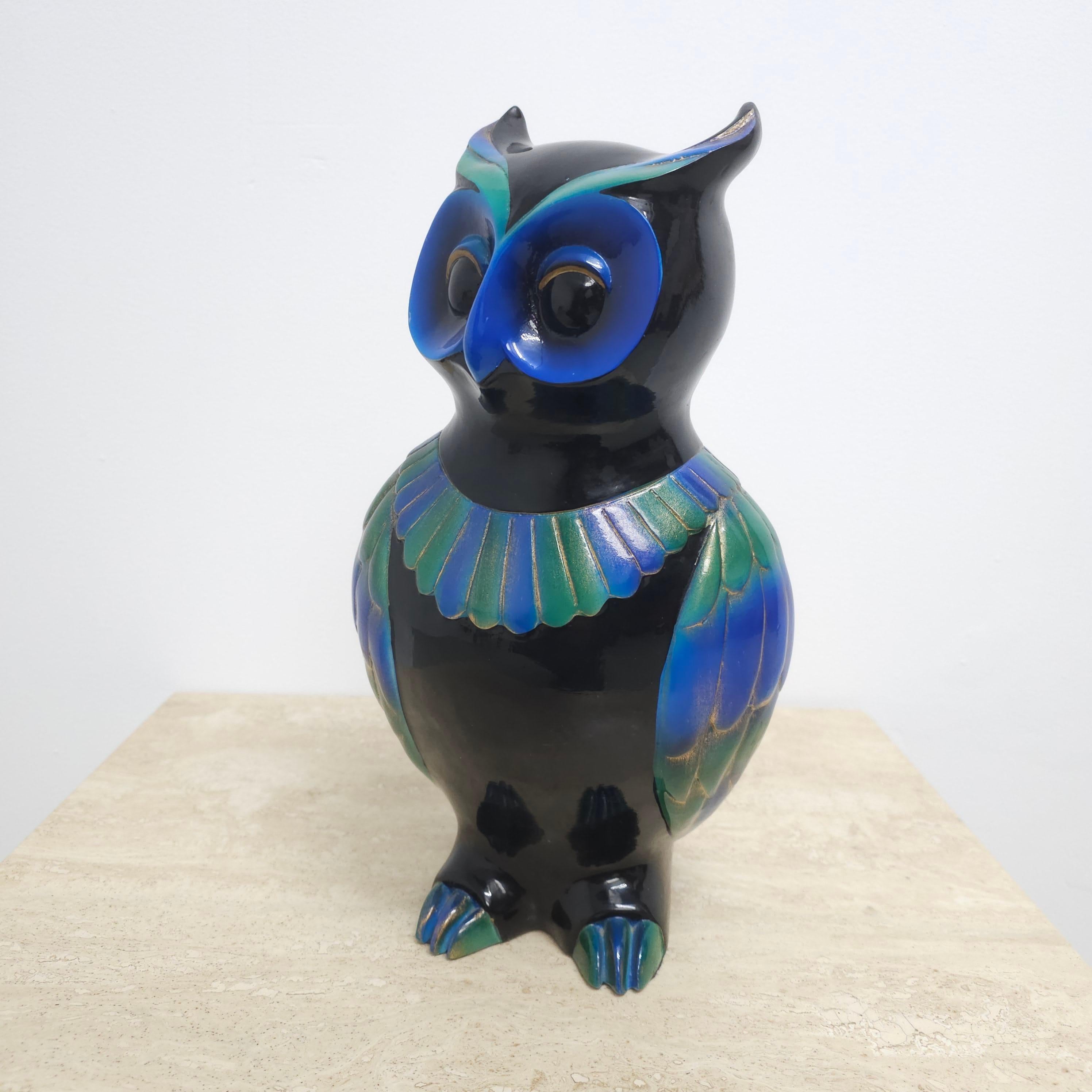 Colorfull hand carved wooden owl. Handmade in Belgium by l'Eau Vive. The base/body is painted in shiny black with strong shiny blue and green in the face and wings, hatched with golden lines and touches. The wood is very thick painted so you almost