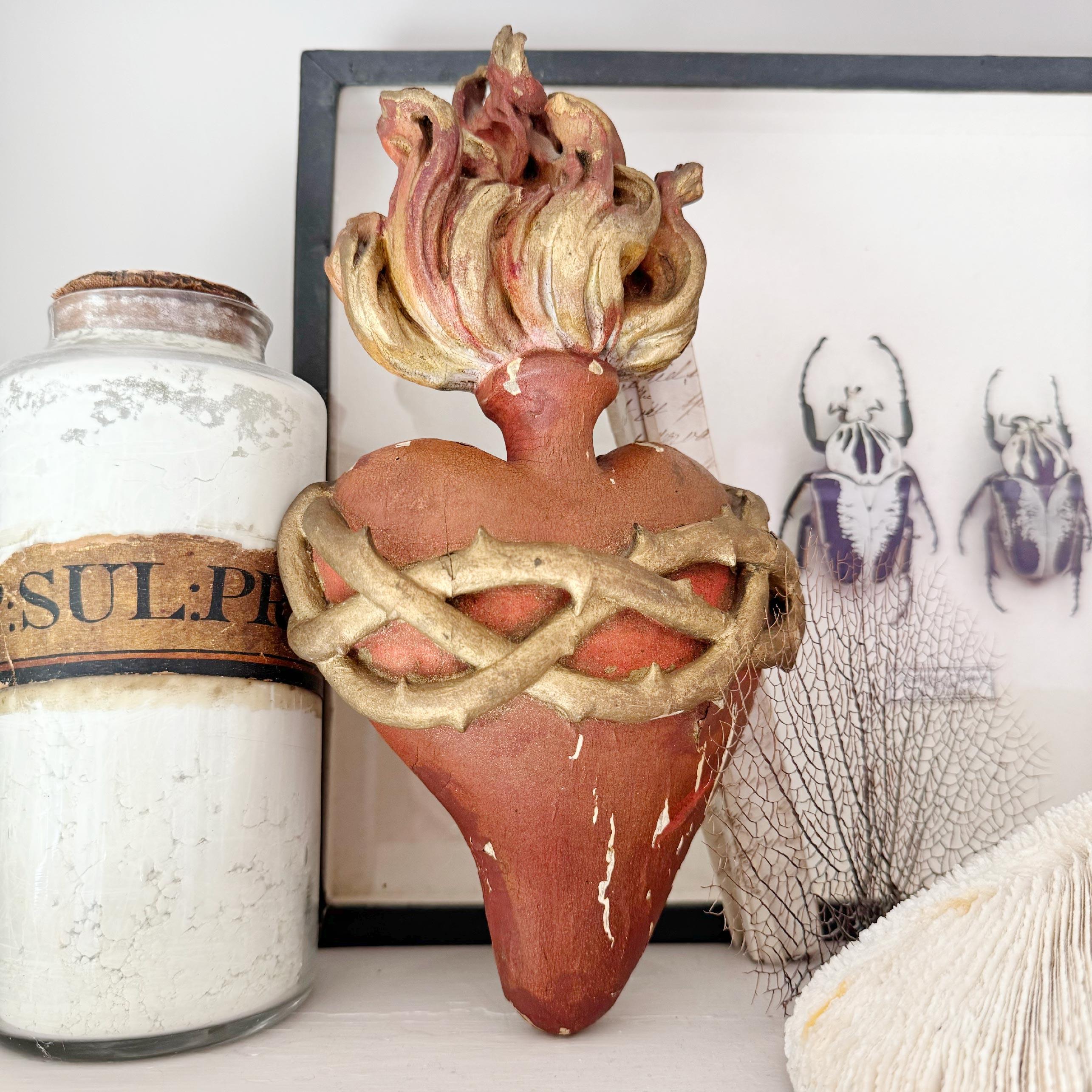 This beautiful Sacred Heart Sculpture dates to 1889 and would originally have hung near the altar in a German Church. The heart is crafted from wood with a gesso covering and hand painted, with a carved torchiere to the top it is surrounded by gilt