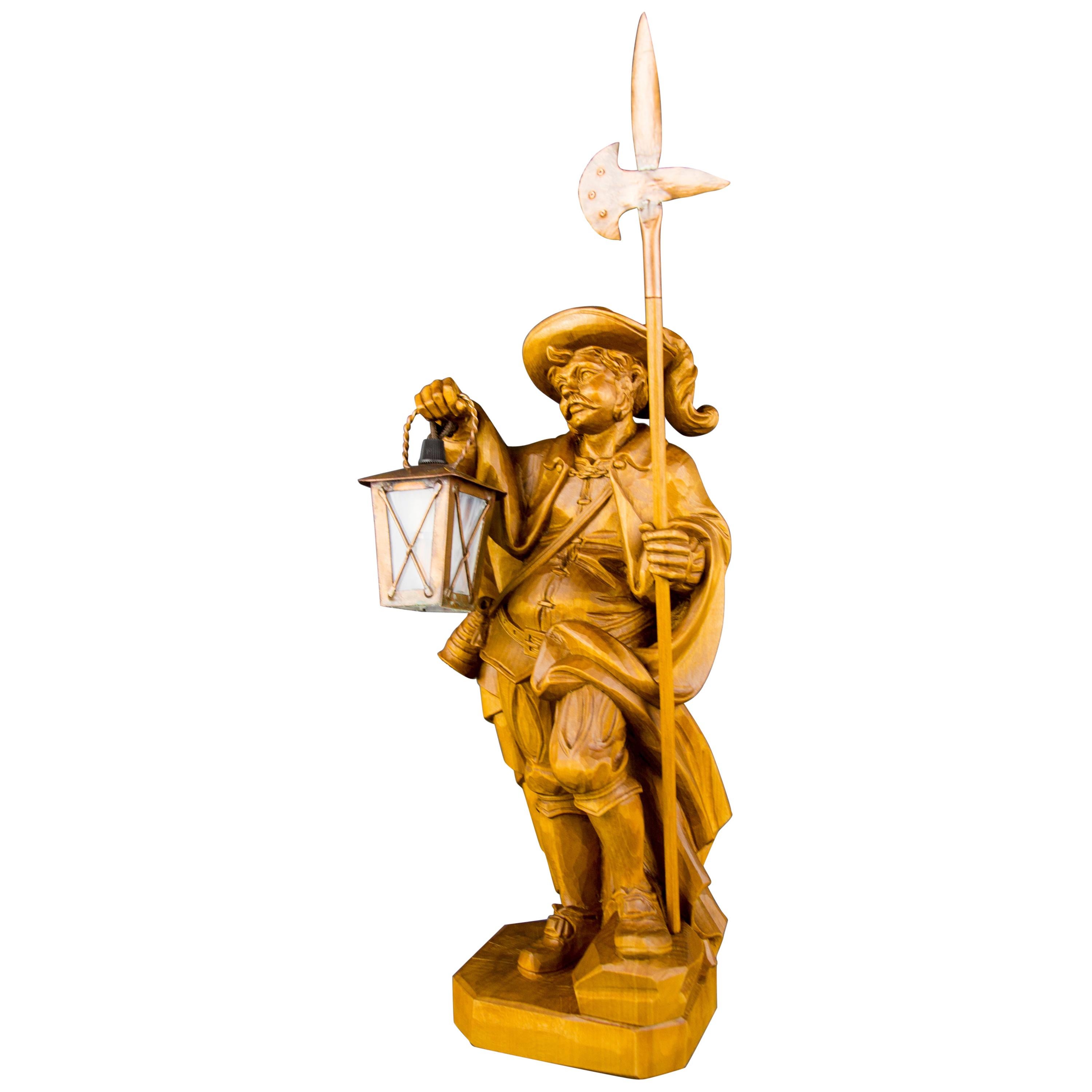 A masterfully hand-carved wooden lamp features a beautiful sculpture of a night watchman with a lantern and halberd. The lantern is made of glass and copper. This beautiful sculpture lamp can be used as a large table lamp. Germany, mid-20th