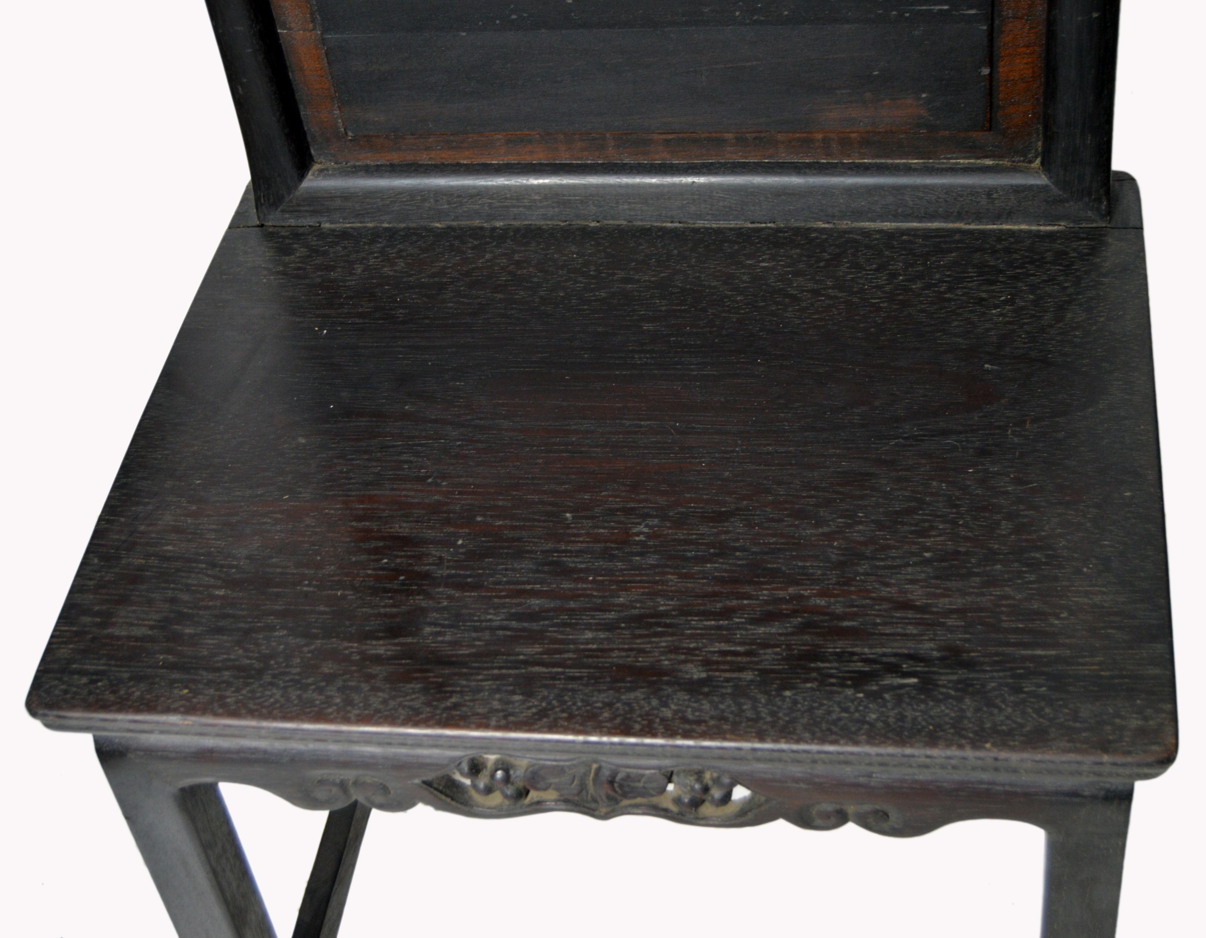 A Chinese Yumu wood side chair from the 19th century, with dark lacquered finish and hand-carved skirt. This Chinese accent side chair features a rectangular molded back topped with a sinuous rail and accented with a central raised panel following