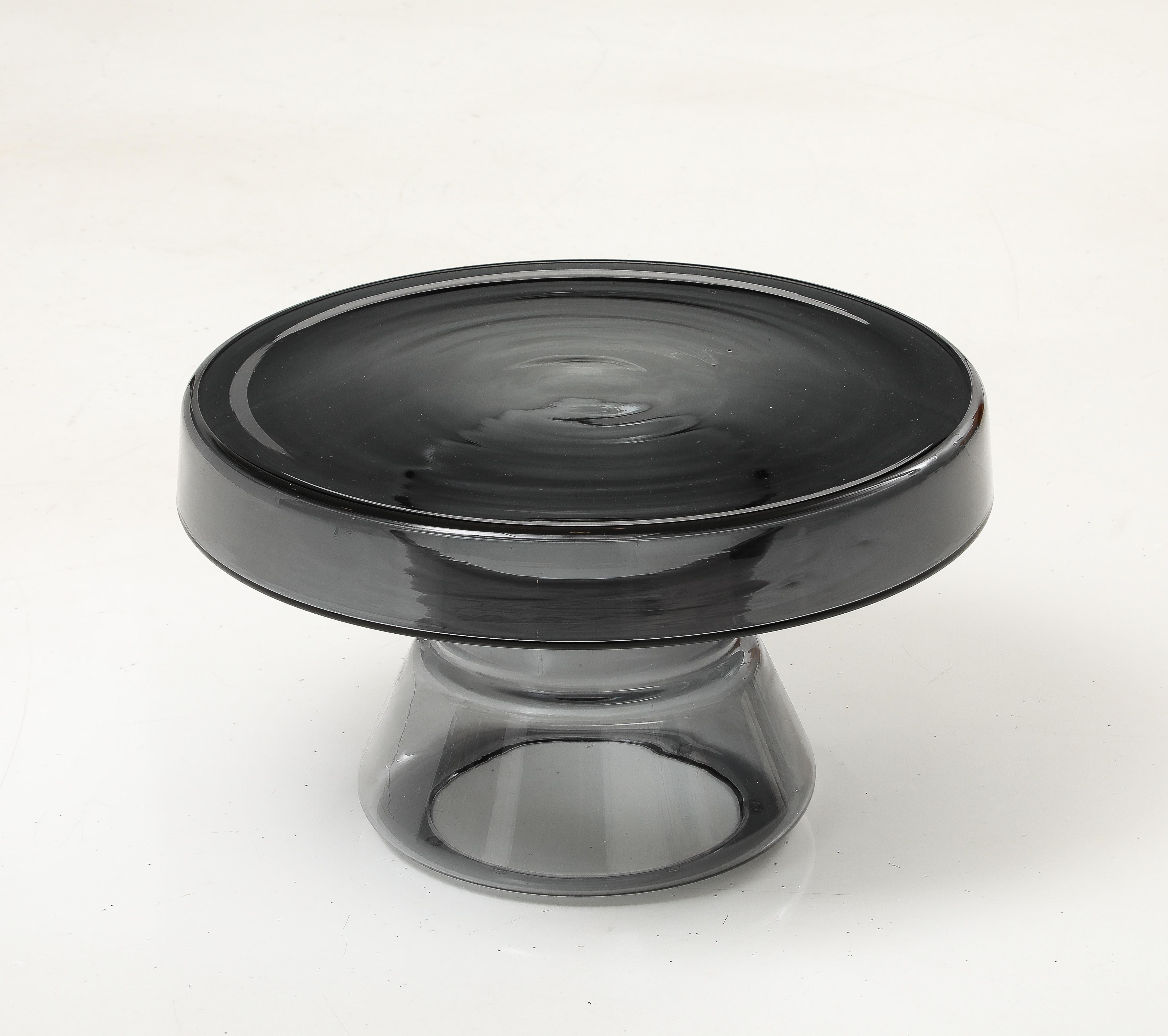 Mesa auxiliar redonda de cristal de Murano gris ahumado, fabricada a mano en Italia. En estas mesas, el vidrio soplado es estructura.  Esta mesa auxiliar o de centro de cristal de Murano de tapa redonda, fundida y soplada a mano, en color gris