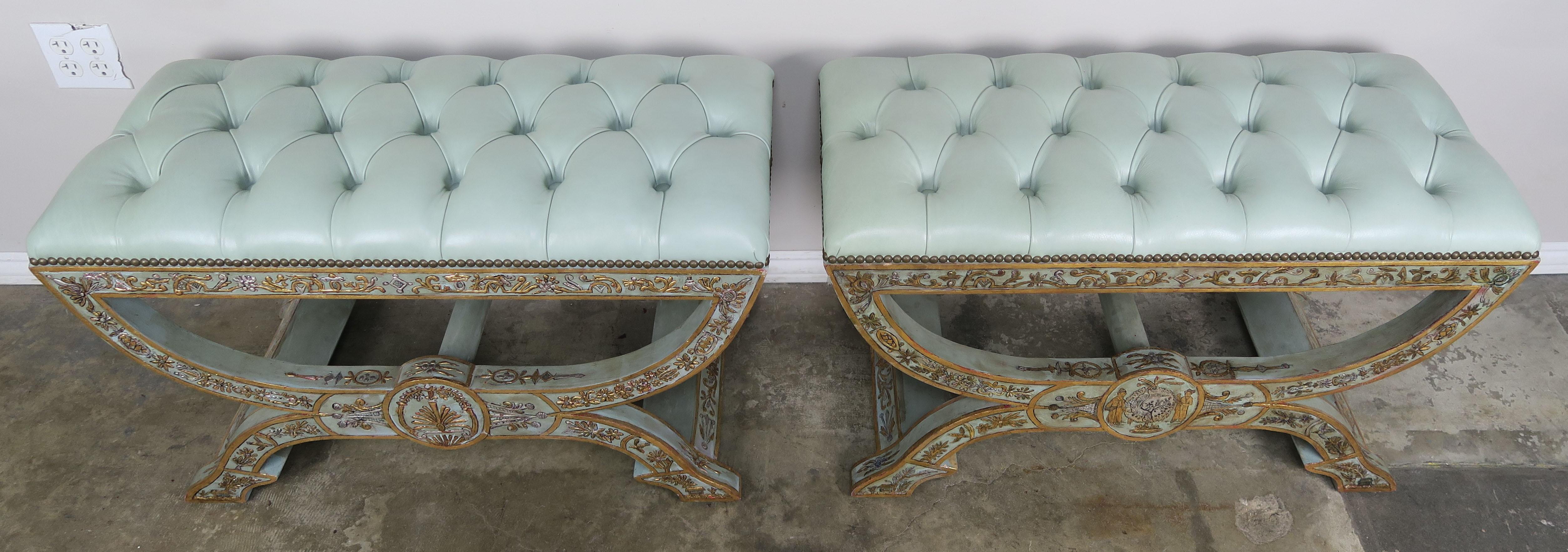 Pair of hand painted benches in gold and silver raised chinoiserie design detailing on a grayish blue background. The benches are upholstered in a tufted soft colored blue leather that coordinates beautifully with the bases of the benches. The