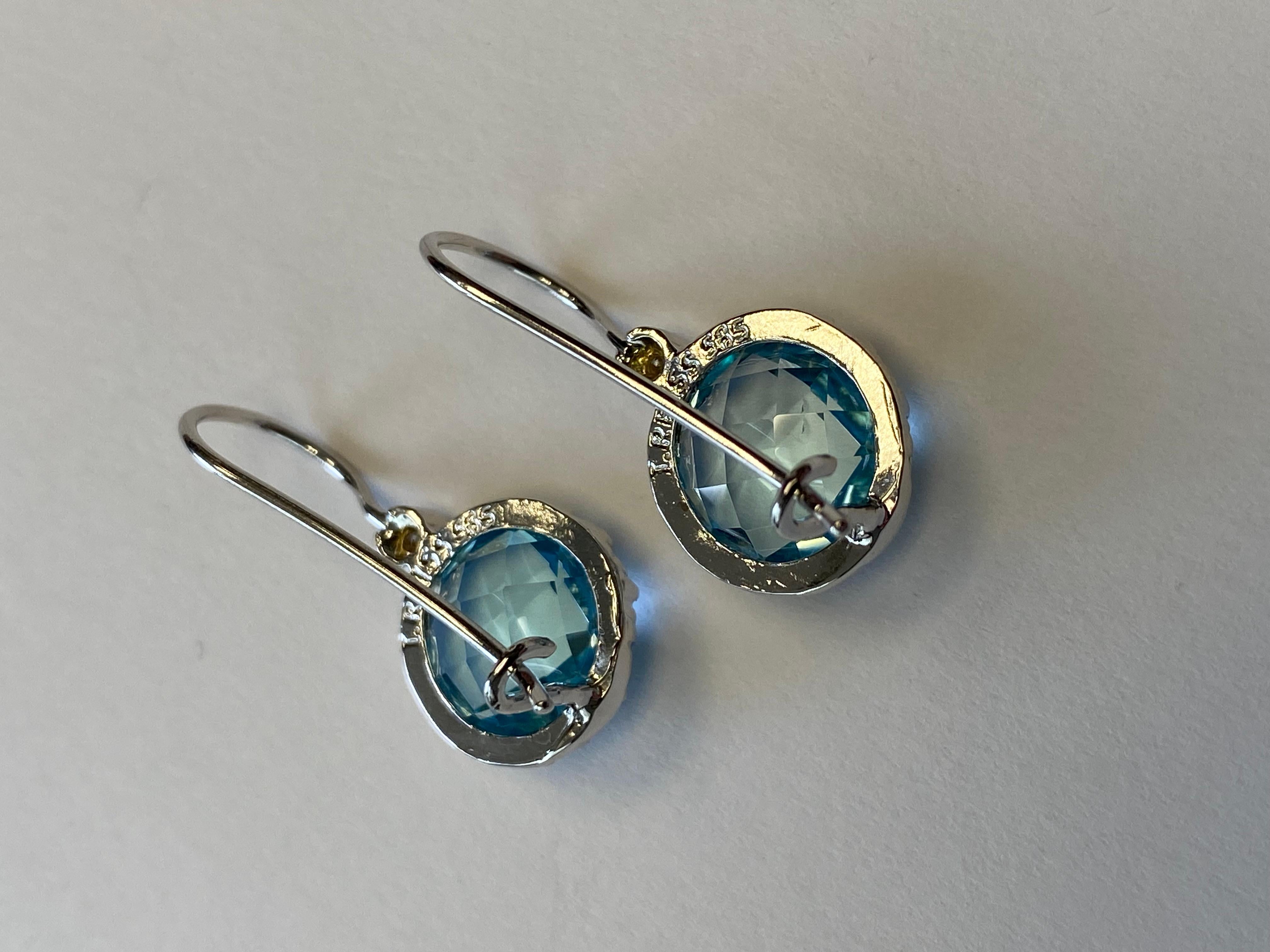 14 Karat White Gold Hand-Crafted Polish-Finished Drop Earrings, Centered with a 10mm 8.5CT Round Checkerboard-Cut Semi-Precious Blue Topaz Color Stone, Accented with 0.03 Carats of Bezel Set Diamonds on a Kidney Wire Back Finding
