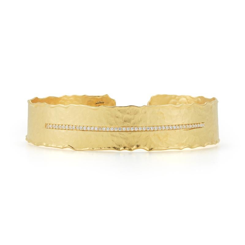 Bracelet manchette ouvert en or jaune 14 carats, mat et fini au marteau, centré de 0,27 carats de diamants sertis en pavé.
