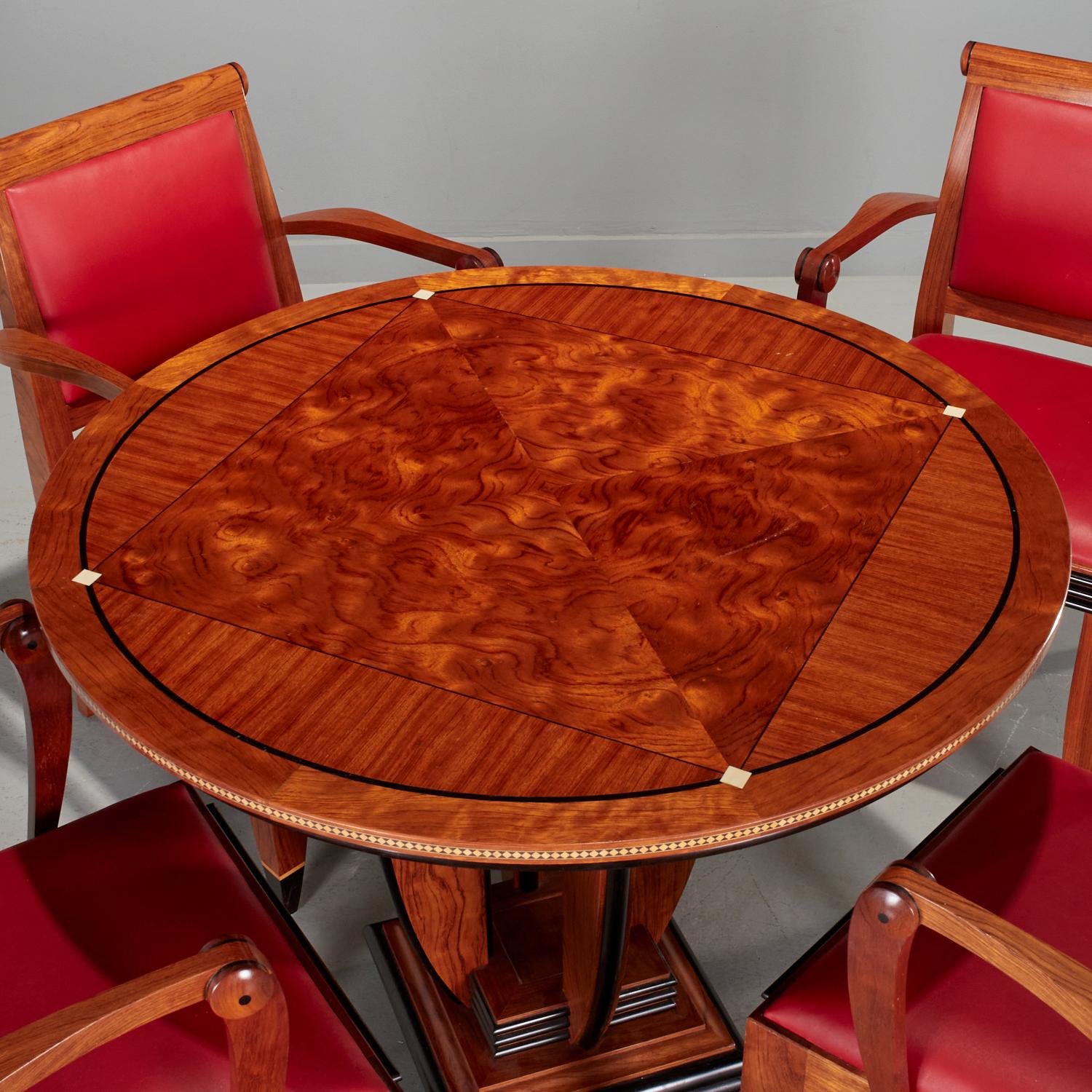 1989, USA, French Art Deco-inspired design. Beautifully constructed of bubinga and ebony, the table raised on open columned standard and central stepped plinth, with a circular inlaid top and four chairs with splayed legs, red upholstery, the backs
