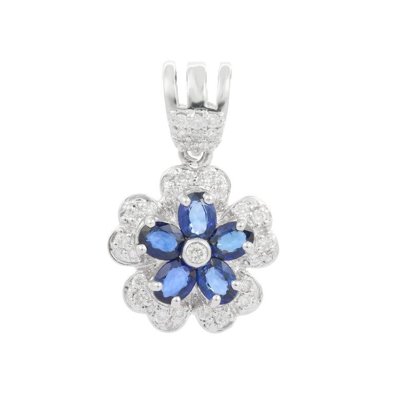 Dieser exquisite Anhänger erblüht vor Eleganz und besticht durch sein fesselndes Blumendesign, das in strahlendem 18-karätigem Weißgold gefertigt ist. Sein Herzstück ist ein Cluster aus lebhaften blauen Saphiren im Ovalschliff von insgesamt 0,95