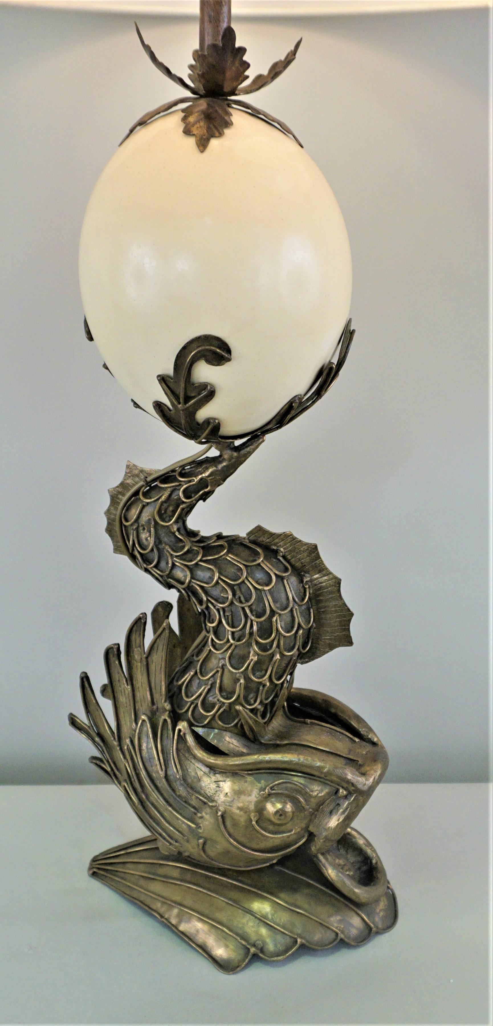 An ostrich egg sting above a handcrafted bronze dolphin as table lamp fitted with silk hardback lampshade.