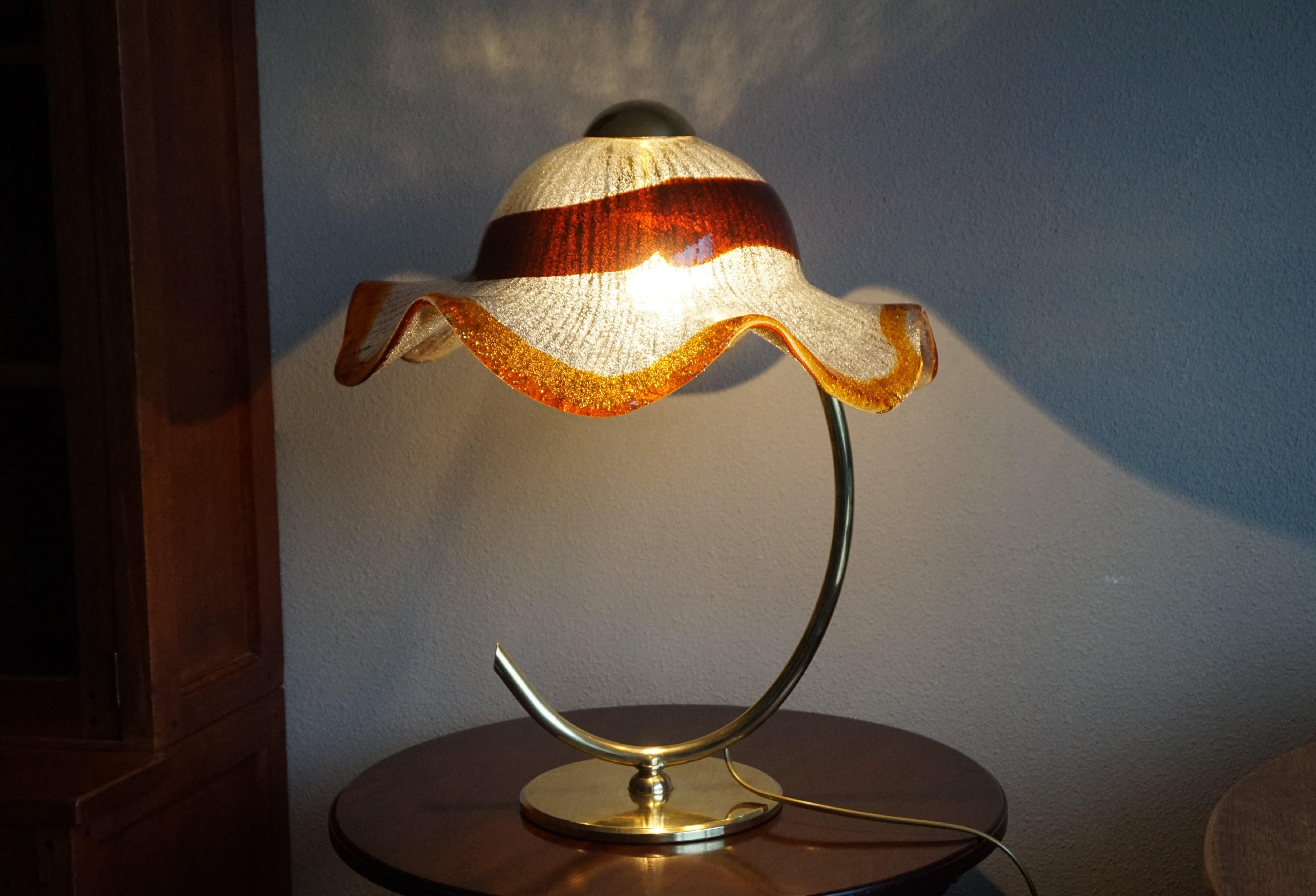 Italian art glass elegance combined with a very stylish brass base.

This rare and highly stylish table lamp from midcentury Italy is like a lady in an elegant summer hat. This Murano light fixture breathes nothing but class and great style and it