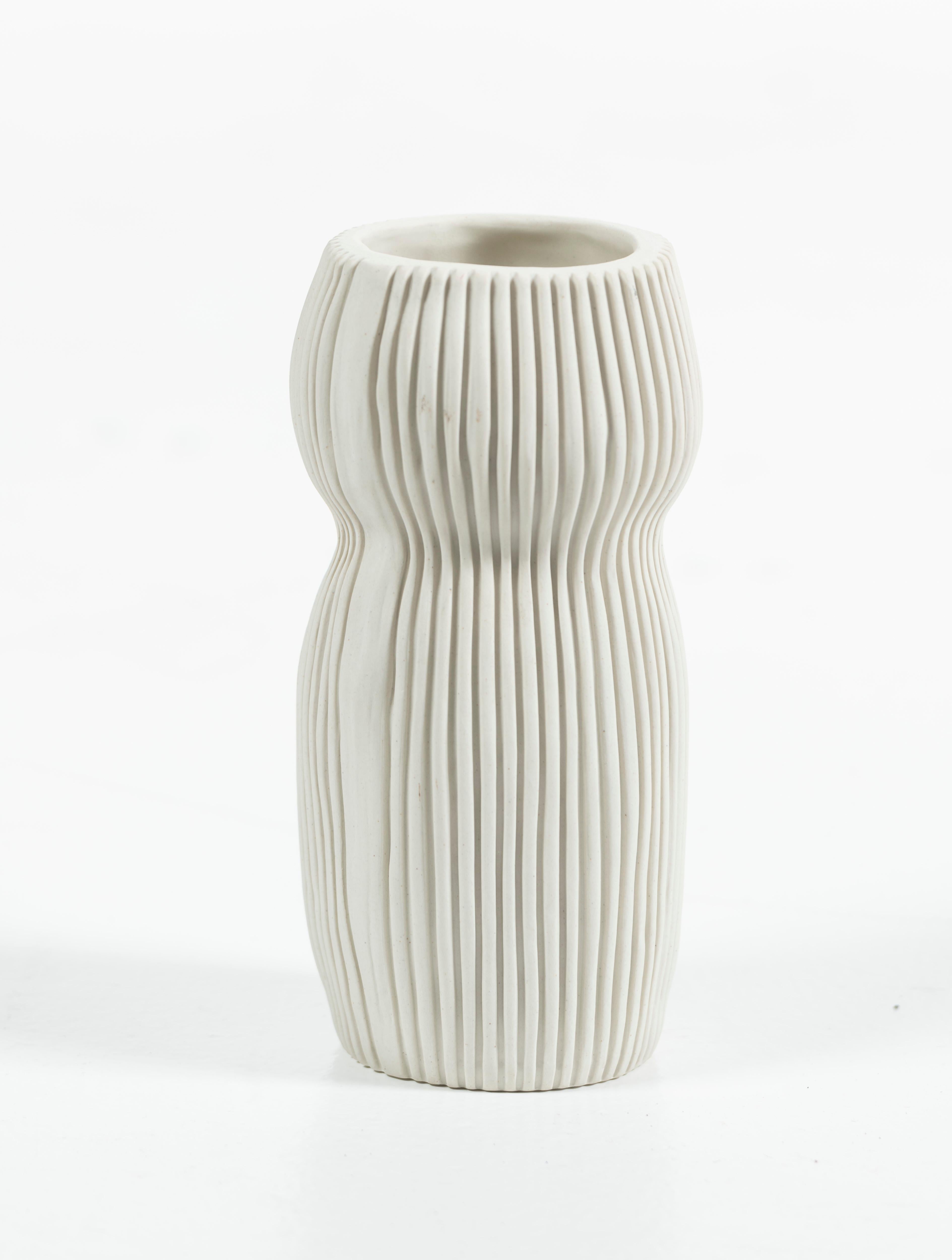 Modern hand-thrown ceramic vase in cream with vertical grooves along the side.  Signed on the bottom, artist unknown, this vase can hold flowers, decorate your shelves or tables on its own or as part as a grouping. Great gift. 