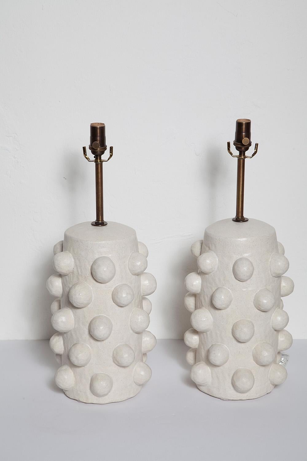 Pair of custom white glazed stoneware lamps, handcrafted exclusively for Stripe by ceramicist Priscilla Hollingsworth. Antiqued brass hardware with white fabric cords.