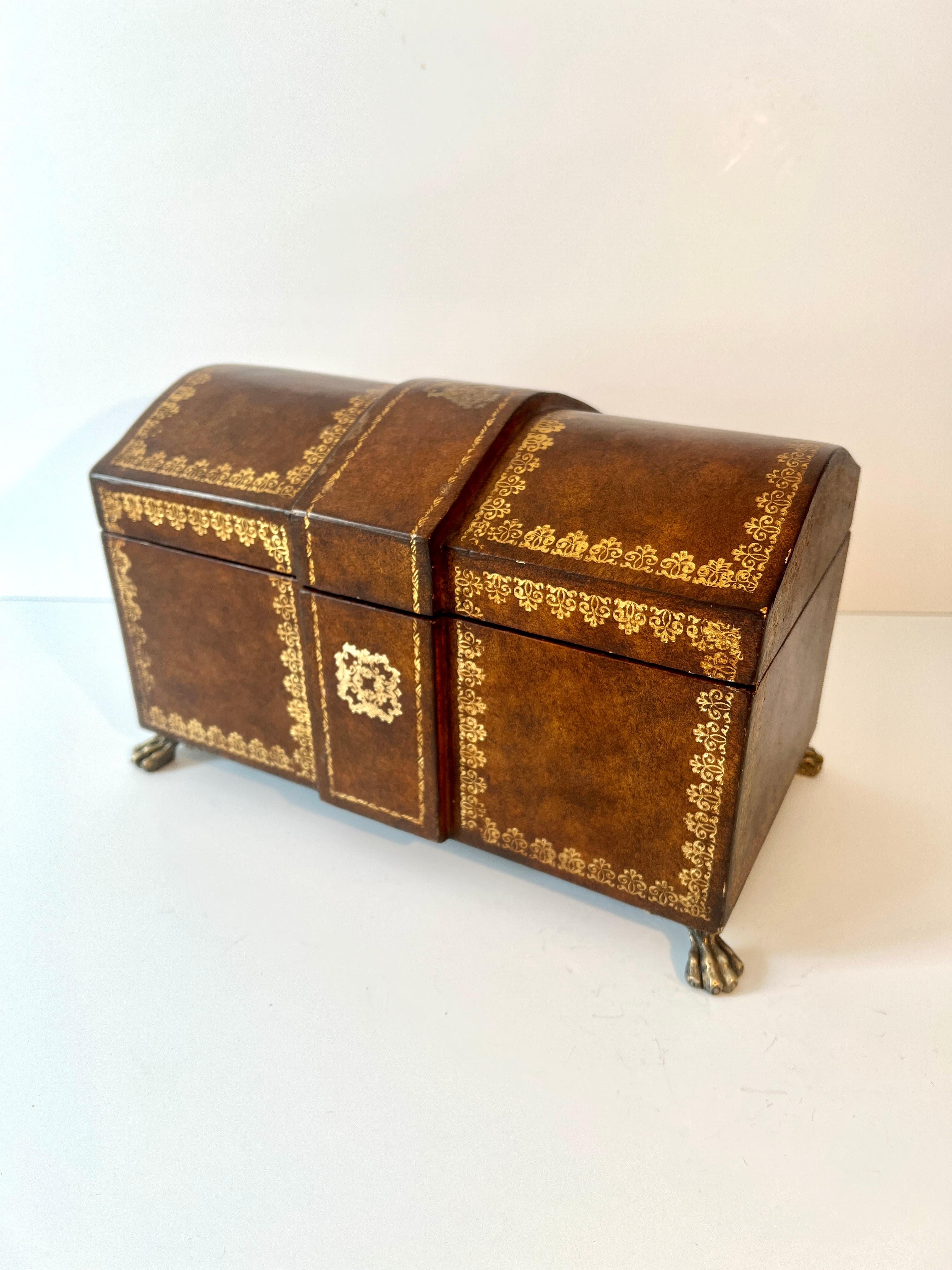 Un joli coffret en cuir avec du cuir doré.   En forme de boîte à trésors, avec une partie centrale surélevée, la boîte est unique par sa forme et son style.

Un complément à tout bureau pour ranger les papiers, les recettes ou les objets plus