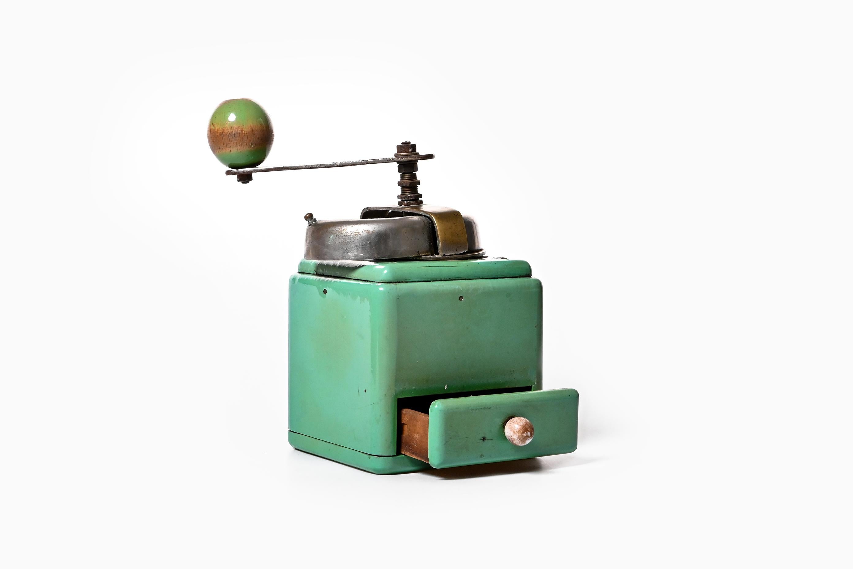 Midcentury styled manual coffee grinder from the 1930s is out for sale. The handcrafted wooden body of the grinder is coated with a mint colored celluloid paint, lending a bright jolly look for this vintage product. The paint around the edges is