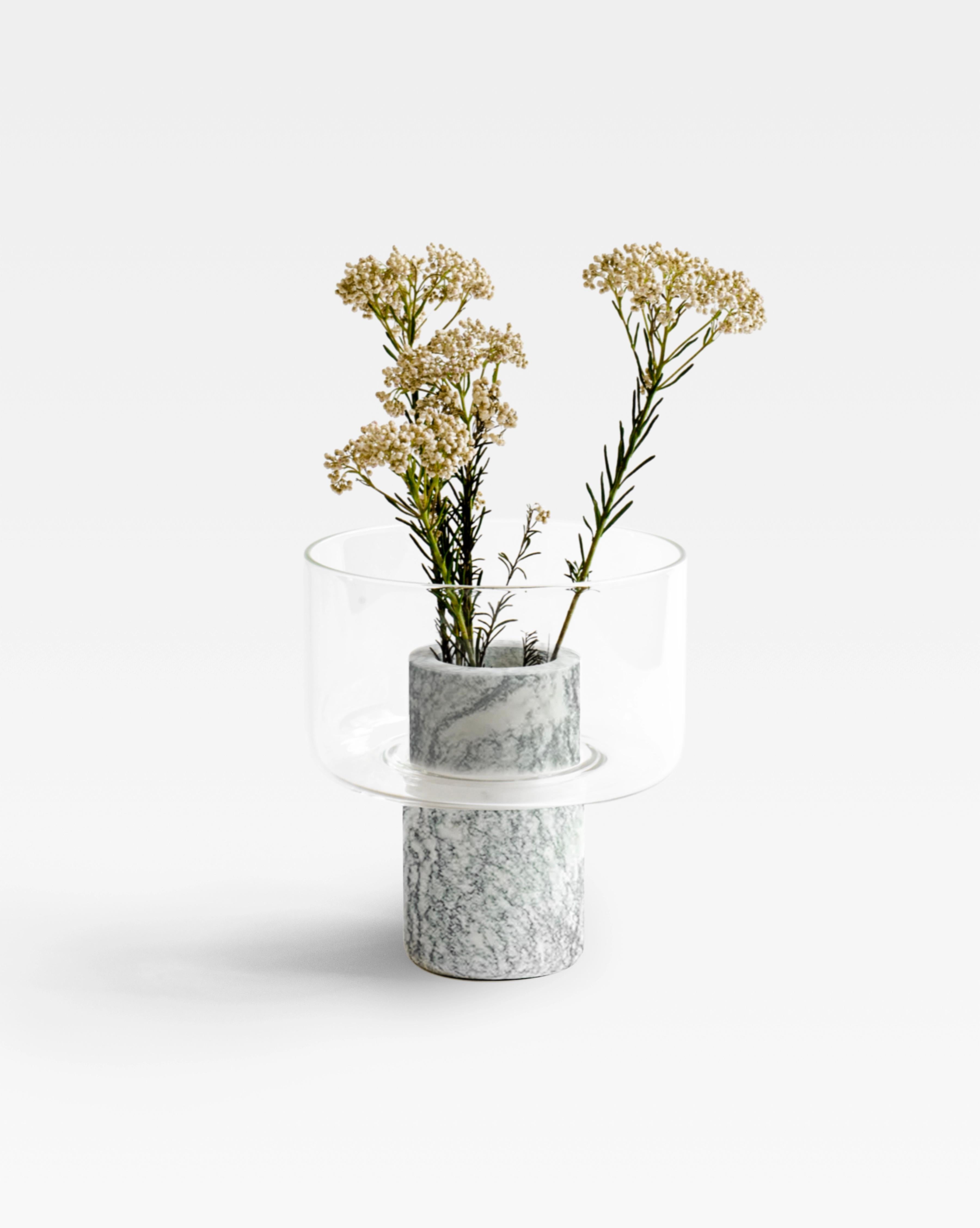 A glass and marble vase to add a touch of softness and detail to the interior. The thin and delicate material of the top contrasts the marble body of the base and creates a layered silhouette. The Italian word 