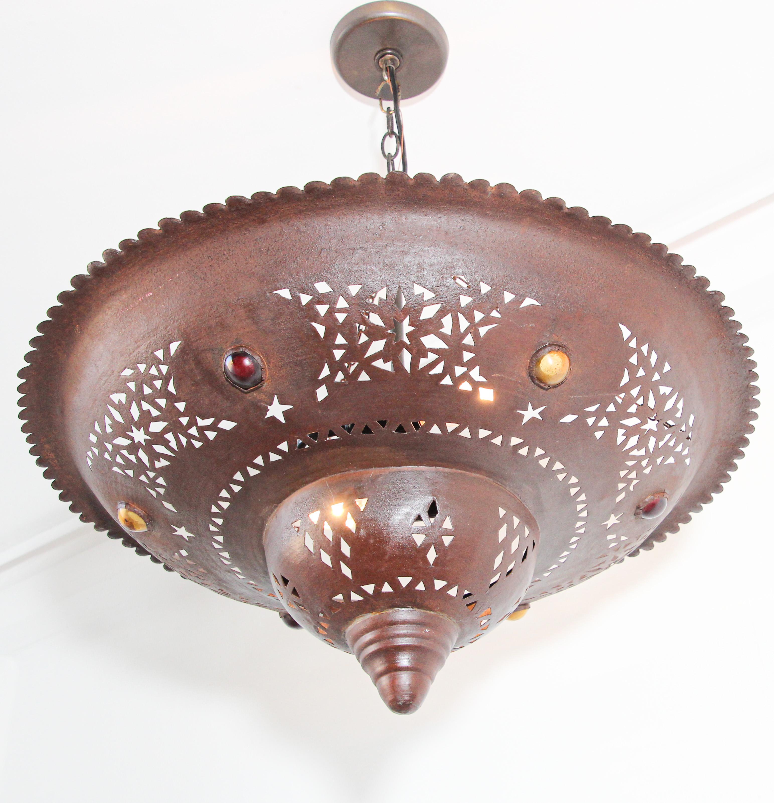 Handcrafted large Moroccan metal chandelier handcut with Moorish design.
Brown dark color metal hammered and inlaid with round jeweled colored glass in red and amber.
Rewired ready to use.
Additional chains could be added to your