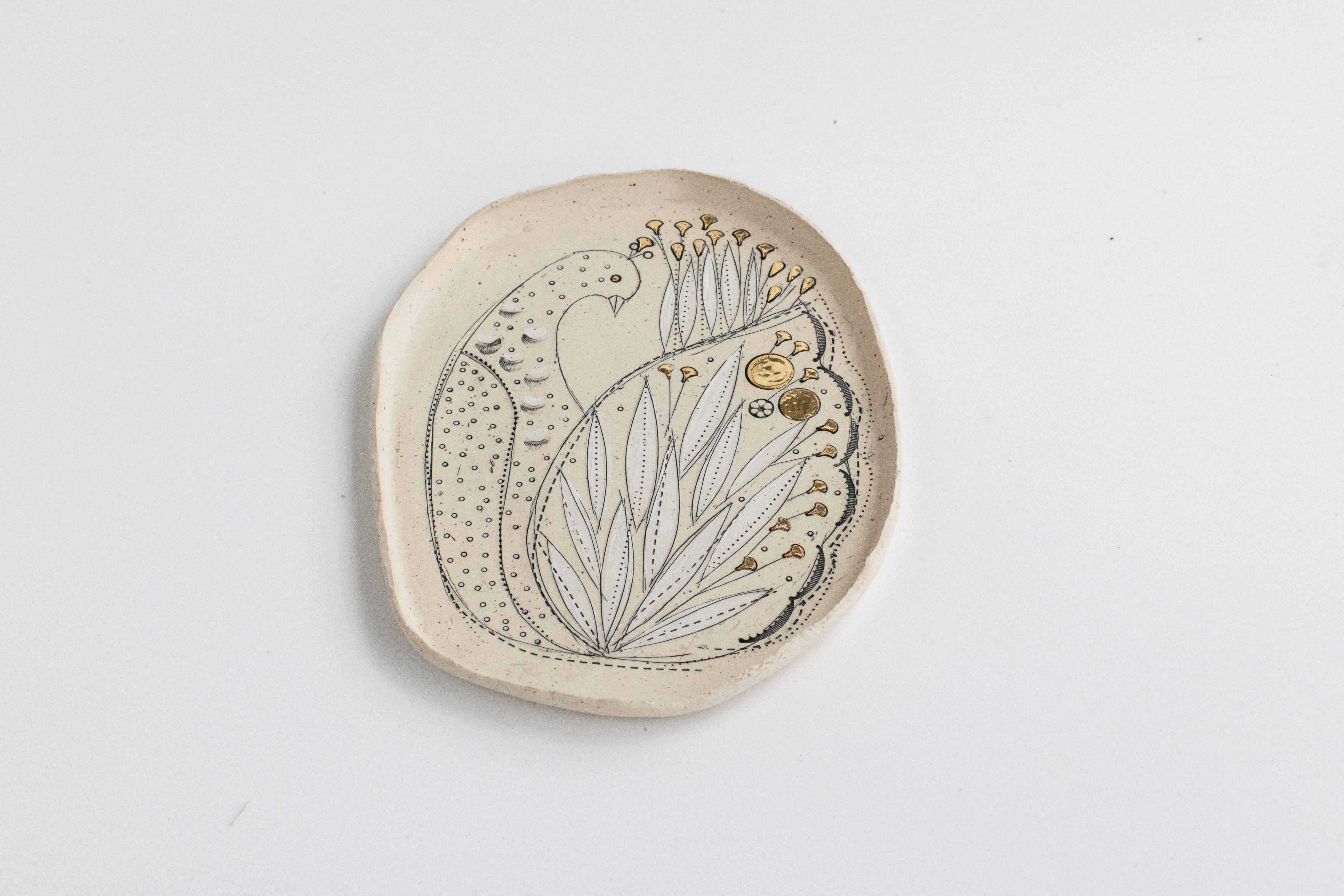 Un vassoio leggero e delicato realizzato a mano, dalla forma organica e con un bordo strappato in argilla naturale non smaltata e maculata.
Adornato con una decorazione esuberante di pavone stilizzato.
La decorazione è realizzata con il mishima,