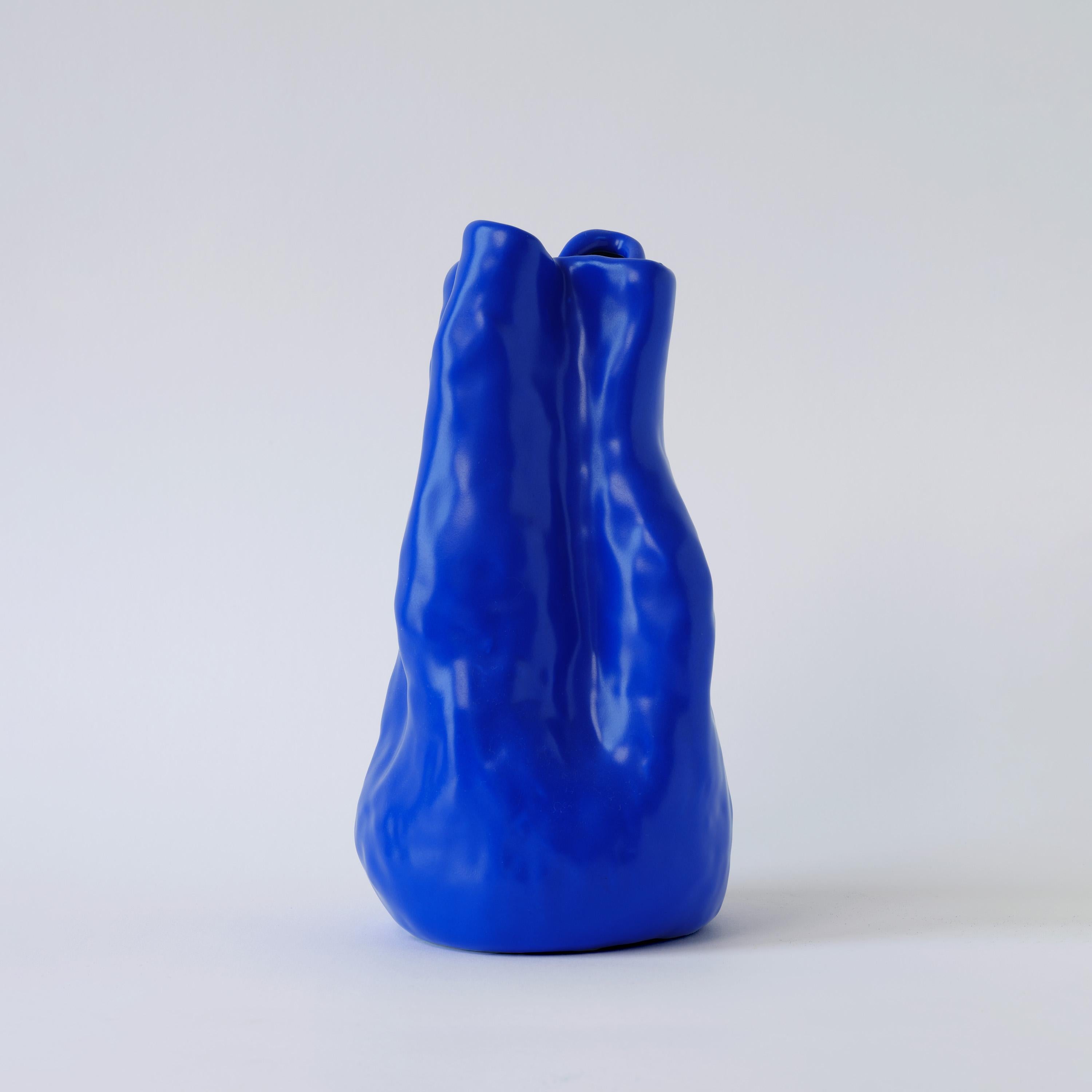 Crafted from fine china porcelain, the Georgia vase radiates a vibrant blue hue and boasts a one-of-a-kind shape, embodying the daring ingenuity of Yves Klein's artistic vision. This unmistakable statement piece infuses any space with a lively,