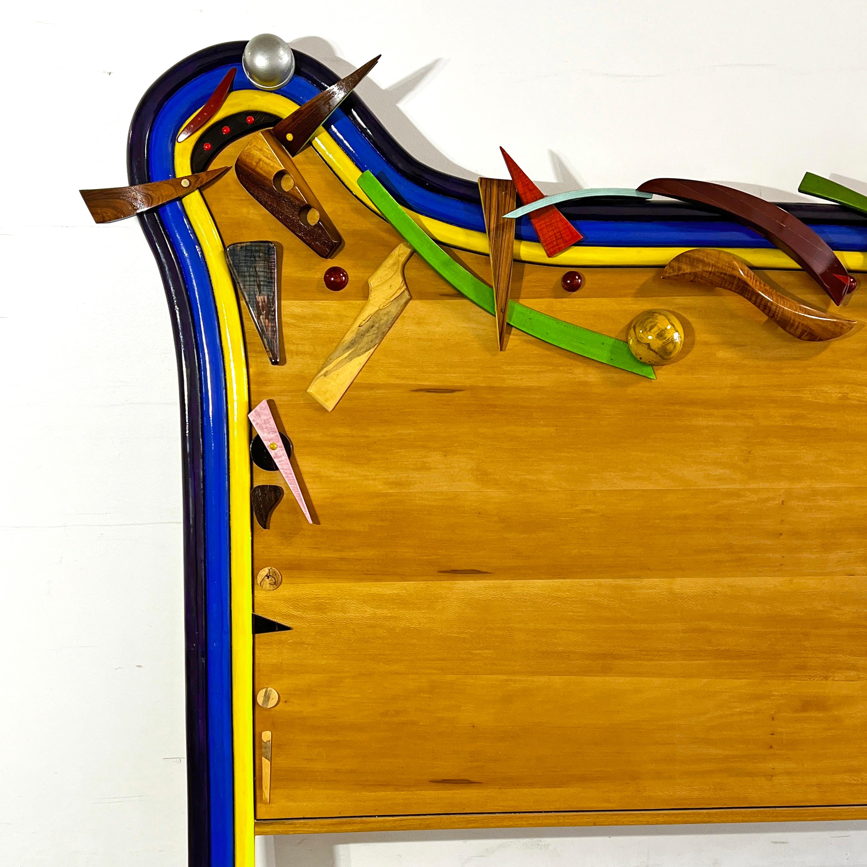 A postmodern artisan made king sized headboard featuring an assemblage of hand carved and lacquered overlays. This whimsical and sculptural construction, by the central Massachusetts artist and fine woodworker Robert G. Field, is dated 2000.

A
