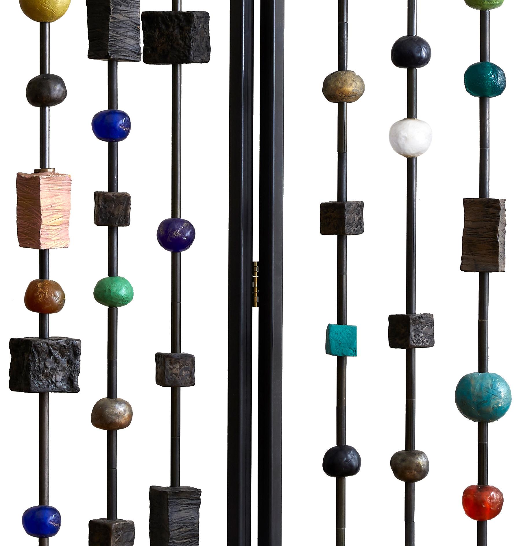 Margit Wittig's triptych blackened metal screen/ room divider features hand-crafted sculptural elements. These pieces can rotate allowing the collector to create varying levels of opaqueness and look of the divider spanning the gamit from full