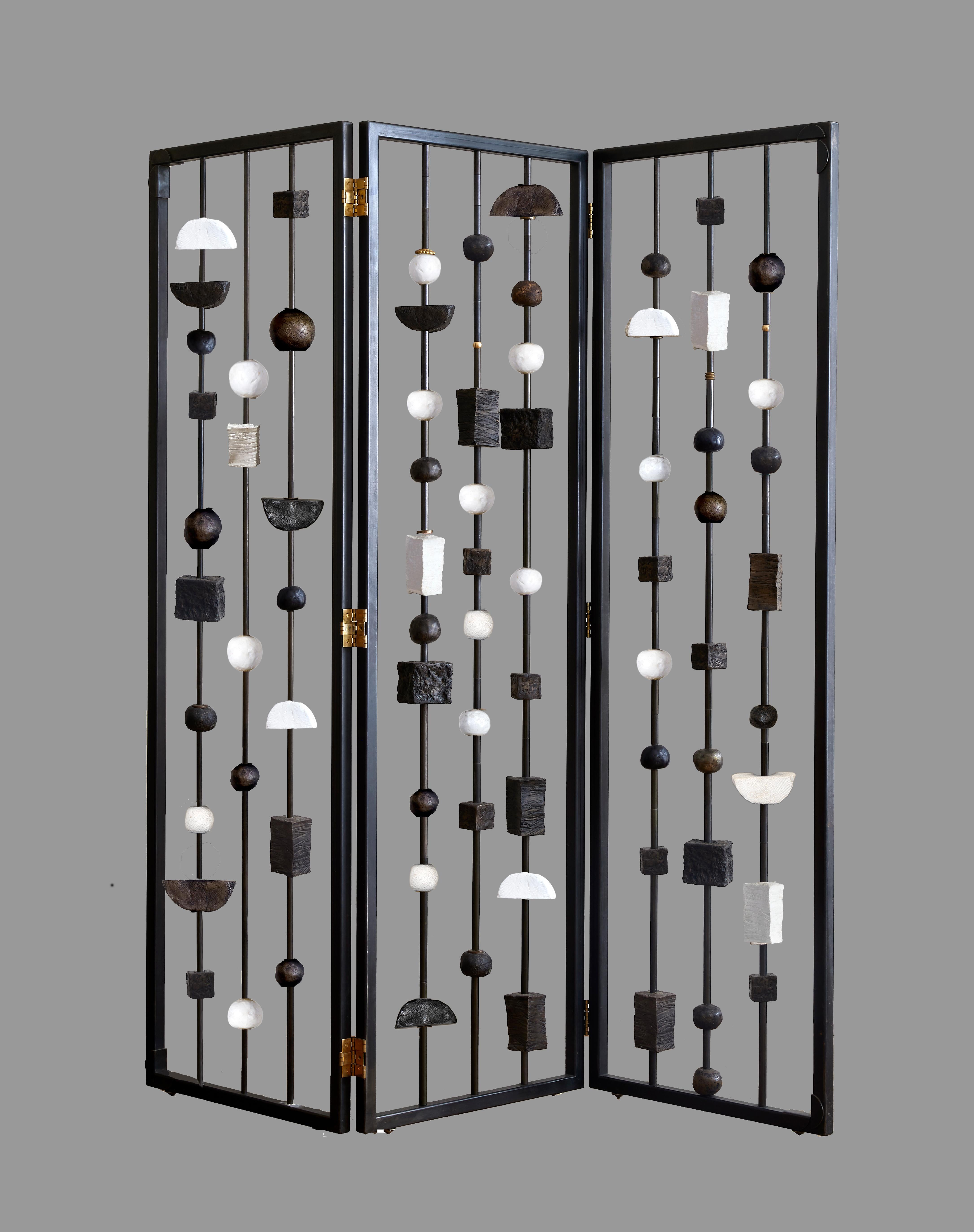 Margit Wittig's triptych blackened metal screen/ room divider features hand-crafted sculptural elements . These pieces can rotate allowing the collector to create varying levels of opaqueness and look of the divider spanning the gamit from full