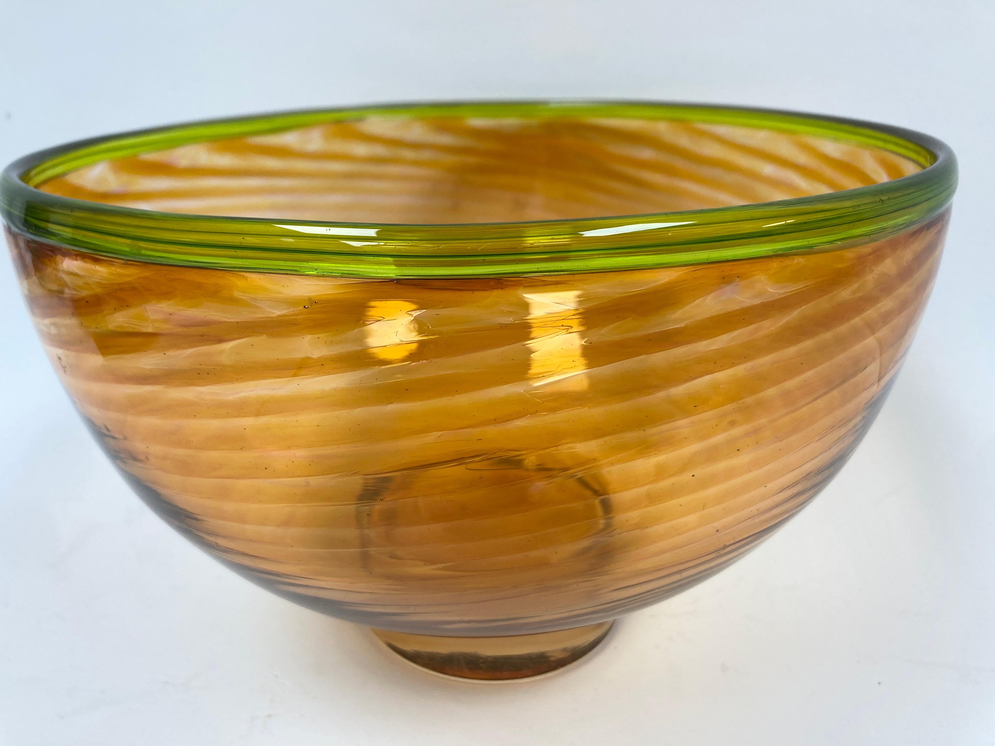 Ciotola di vetro a spirale realizzata dall'artista in un piacevole colore ambrato con bordo verde e base trasparente. Con proporzioni eccellenti, la ciotola ricorda gli oggetti e i vasi in vetro classici italiani degli anni '50 e '60. Firmato e