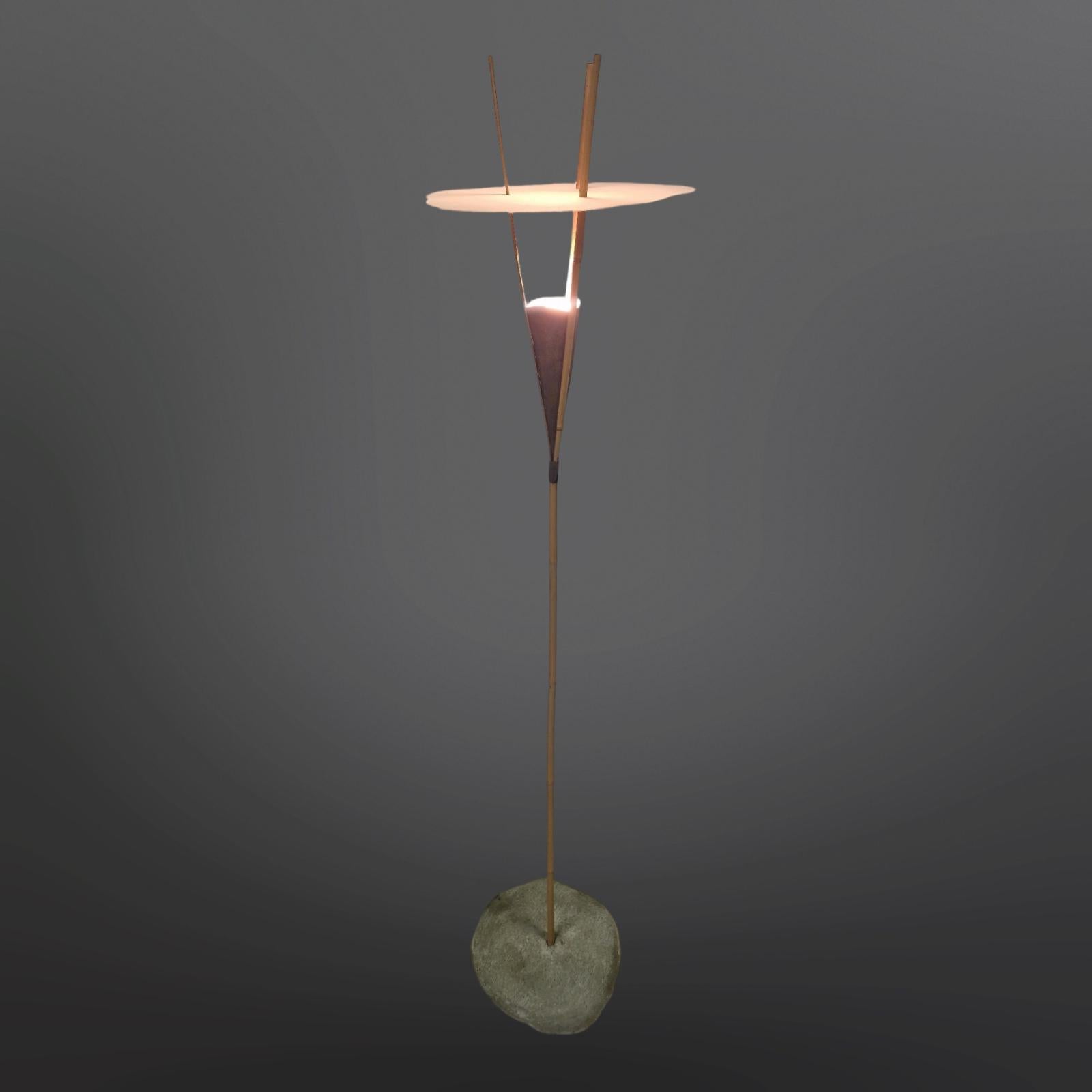 Grande lampada da terra realizzata a mano. Realizzato in bambù, metallo, legno e fibra di vetro.
La base è realizzata in legno con uno strato di cemento che le conferisce l'aspetto di cemento solido. La canna di bambù viene divisa in tre parti e