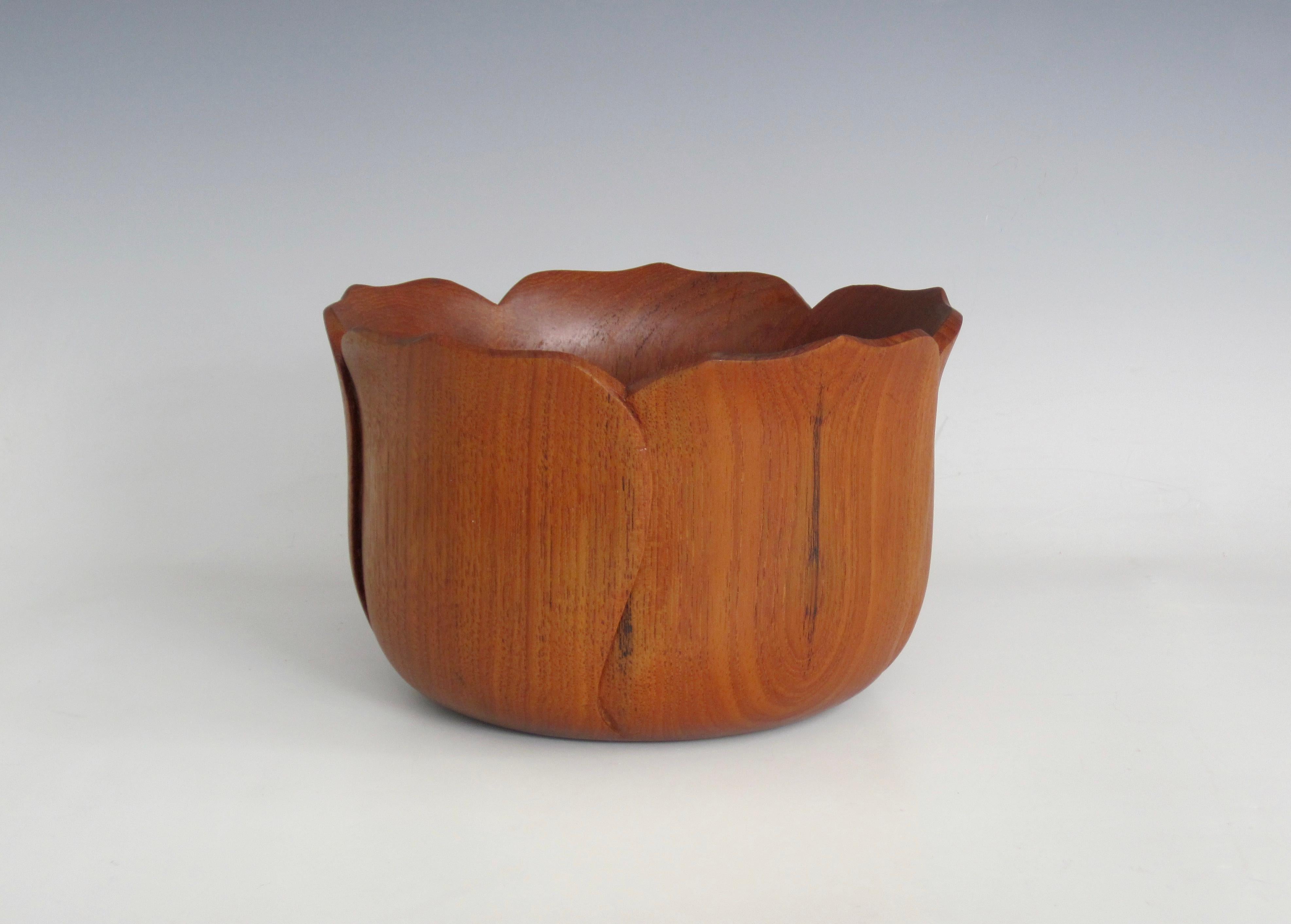 A hand-carved tulip petal shaped teak bowl. I appreciate the handmade curves and the natural wood grain together. It has an earthy feminine essence about it. Lovely for tabletop to hold a myriad of items, display or collection.