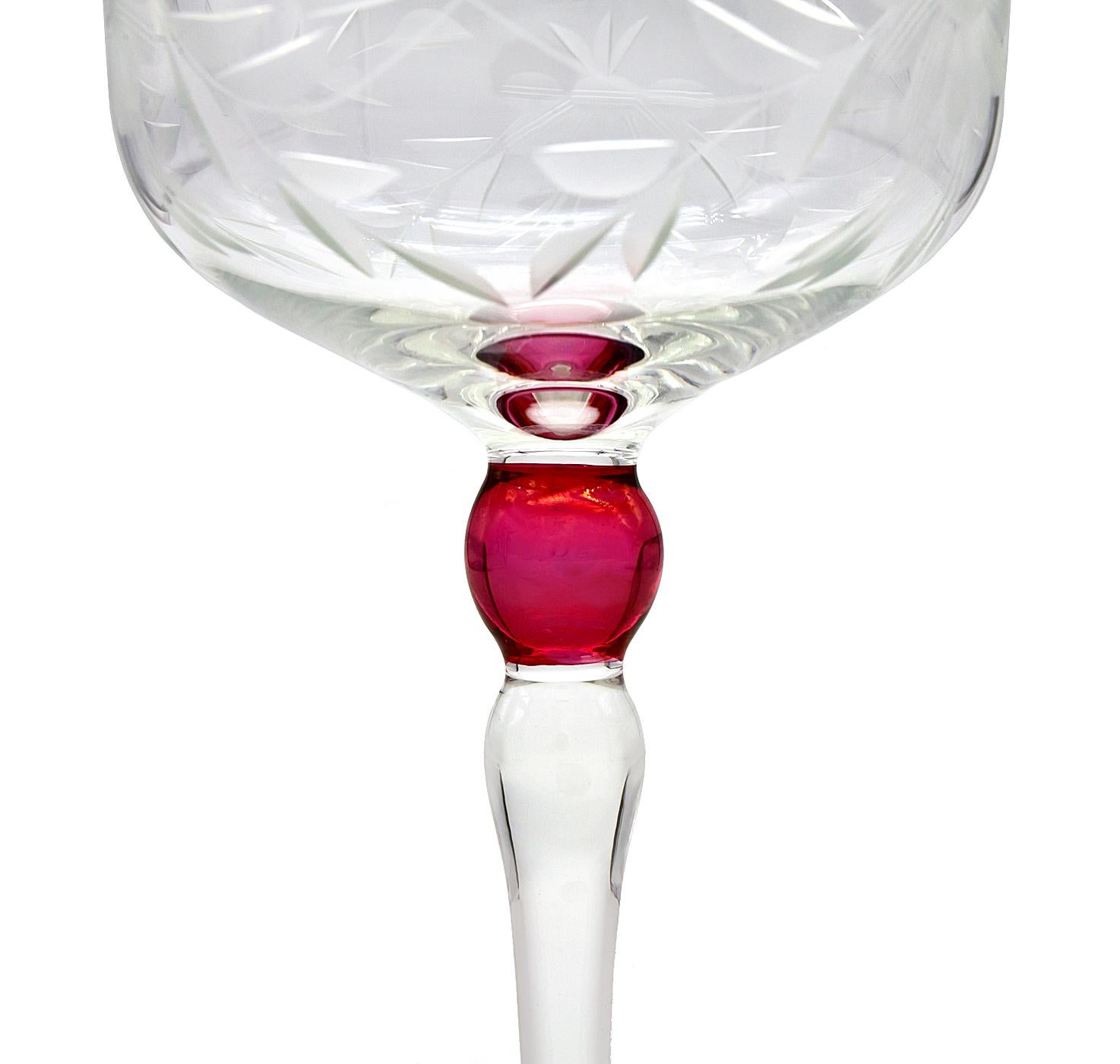 Hand cut crystal champagne coupes, sparkling clarity and elegance. Glasses feature diagonal cuts reminiscent of leaves. Ruby red accent on stem. In great condition.