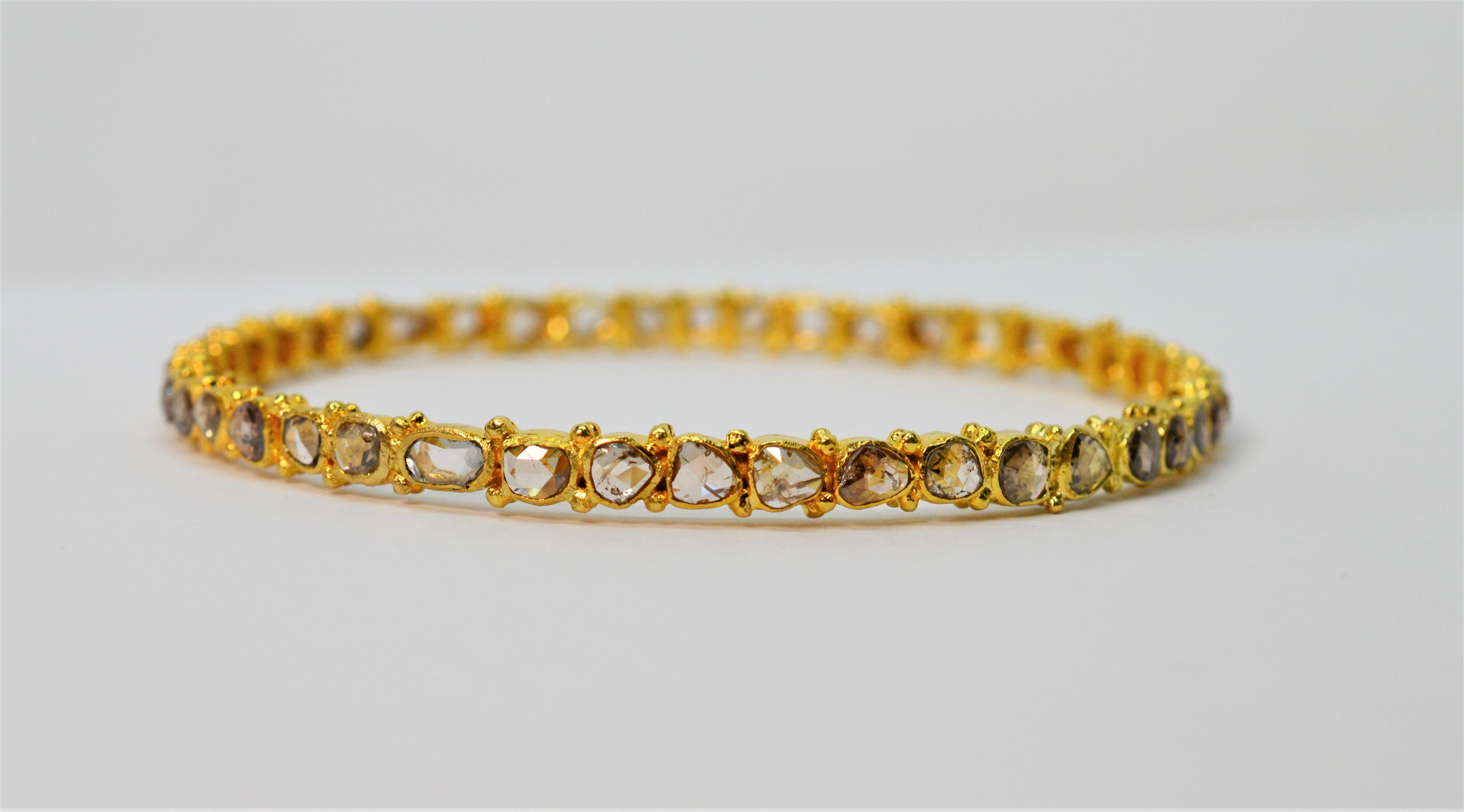 With artisan appeal, this eighteen karat 18K yellow gold hand crafted bangle bracelet displays 4.5 carats total weight of natural hand cut diamonds in various shapes and sizes that are bezel set and contoured in bright yellow gold. The mixed shapes