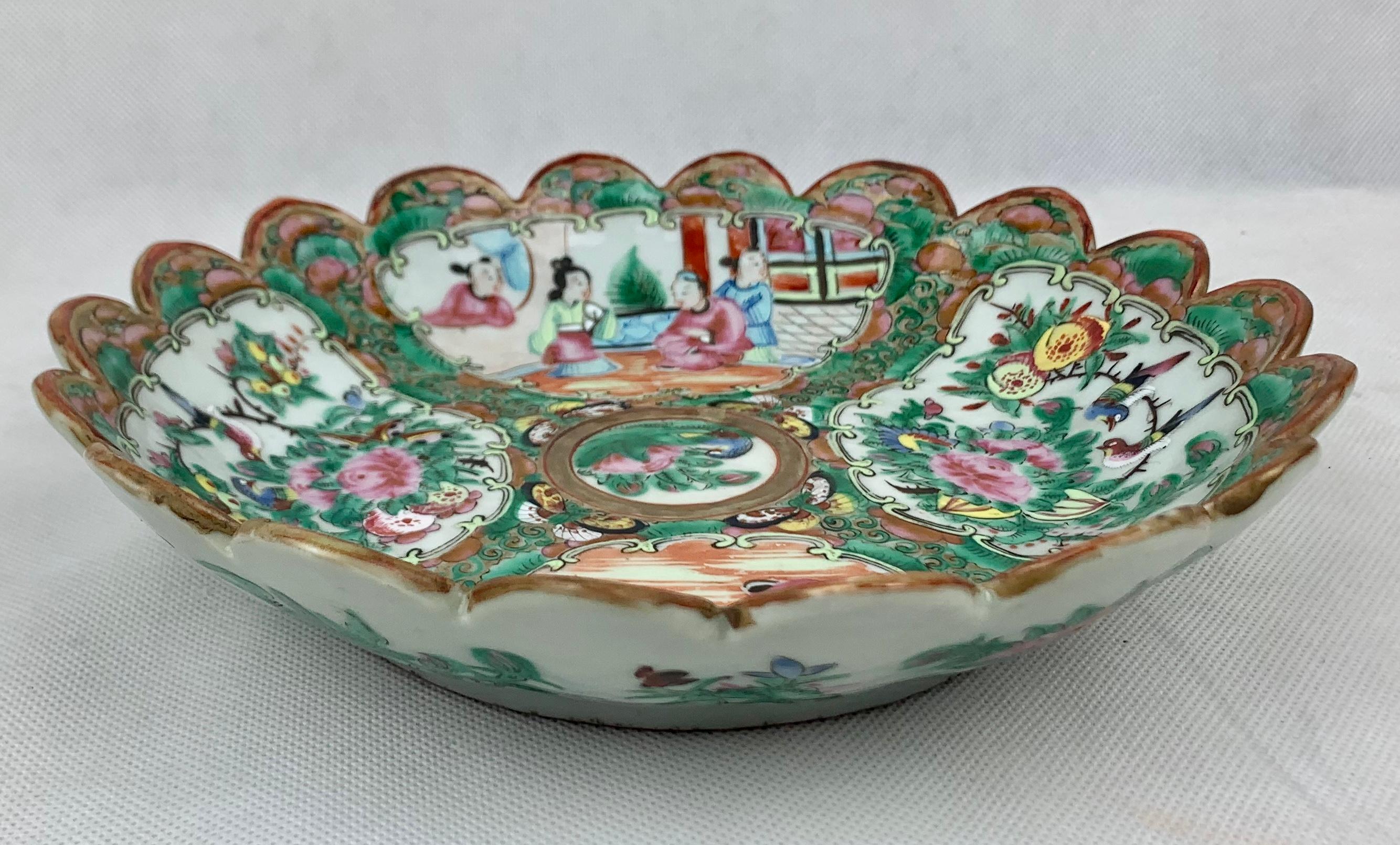 Beautifully executed Rose Medallion porcelain bowl with a scalloped edge. The pattern is divided into four quadrants with two sections showing people interacting and two sections with birds and flowers. The back border of the bowl is hand decorated