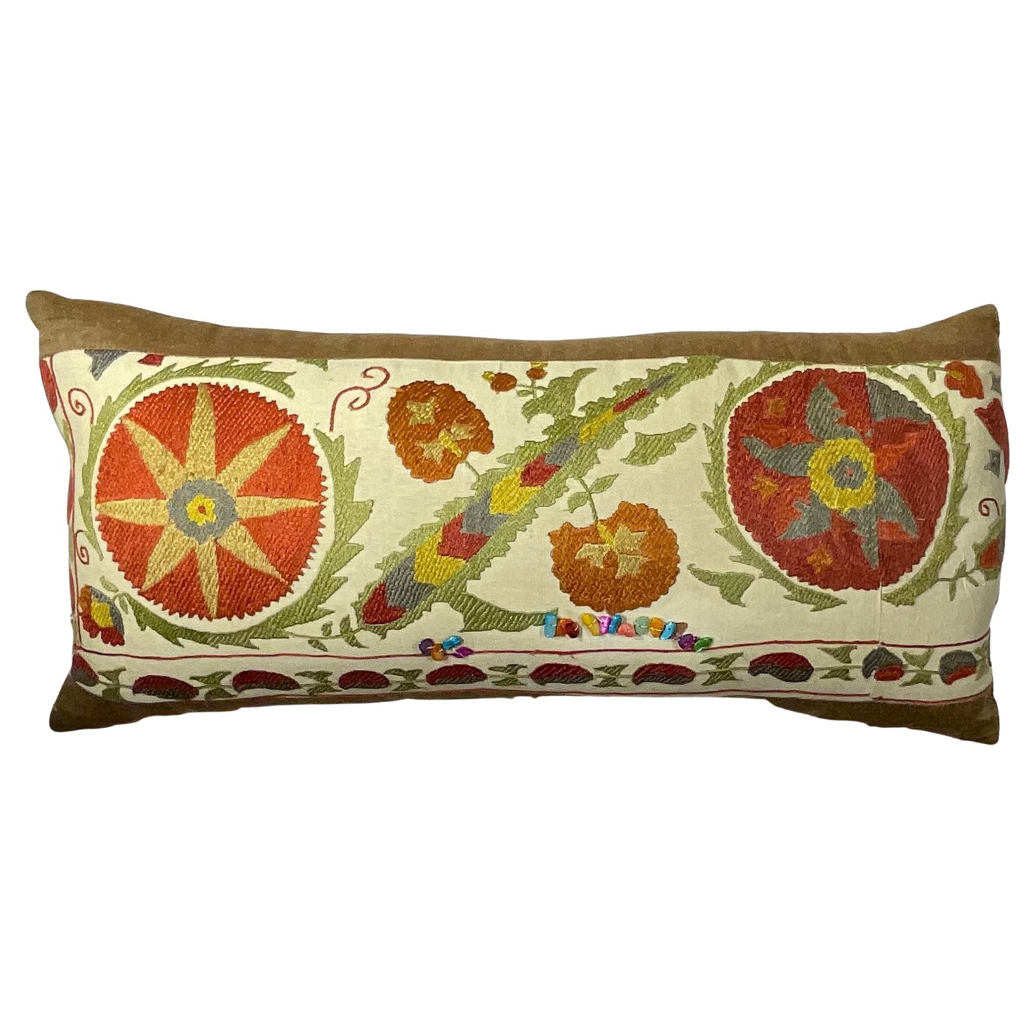 

Aporta un toque de elegancia exótica y encanto artesanal a tu hogar con este exquisito cojín lumbar Suzani bordado a mano. Esta impresionante pieza es más que un simple acento decorativo; es un testimonio de siglos de arte textil de Asia Central,