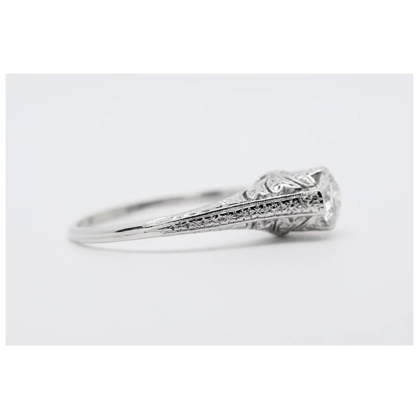 A beautiful hand engraved Art Deco period diamond engagement ring in platinum. In exceptional condition, this original 1920's piece is centered by a sparkling 0.60 carat G color, VS1 clarity antique European cut diamond. The hand crafted mounting