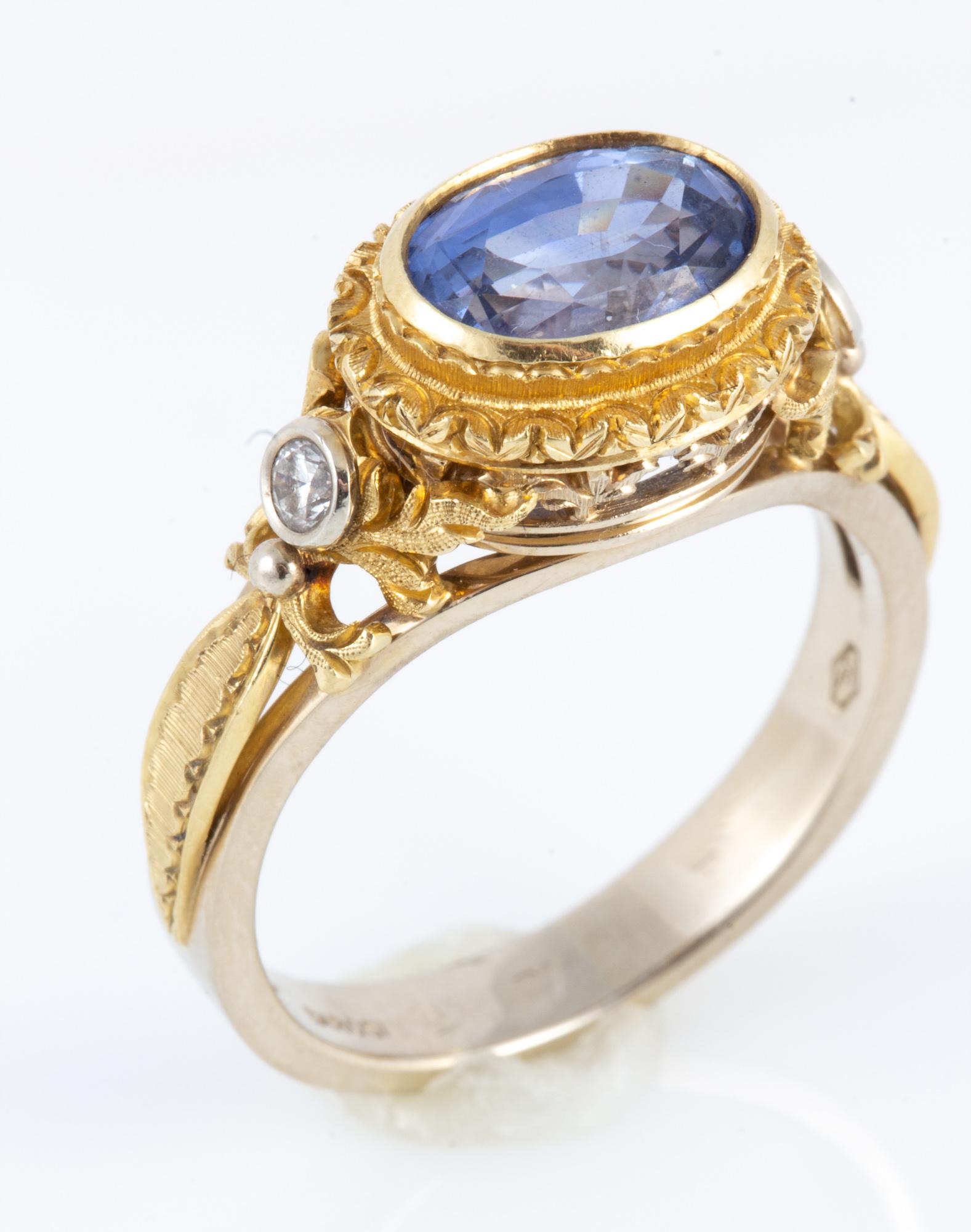 Hand carved and hand engraved two tone 18 kt Gold ring with beautifully cut oval medium blue Ceylon Sapphire flanked by diamonds in an old world setting making it a most romantic piece.

Created by noted jewelry designer David Meelheim Designs, 