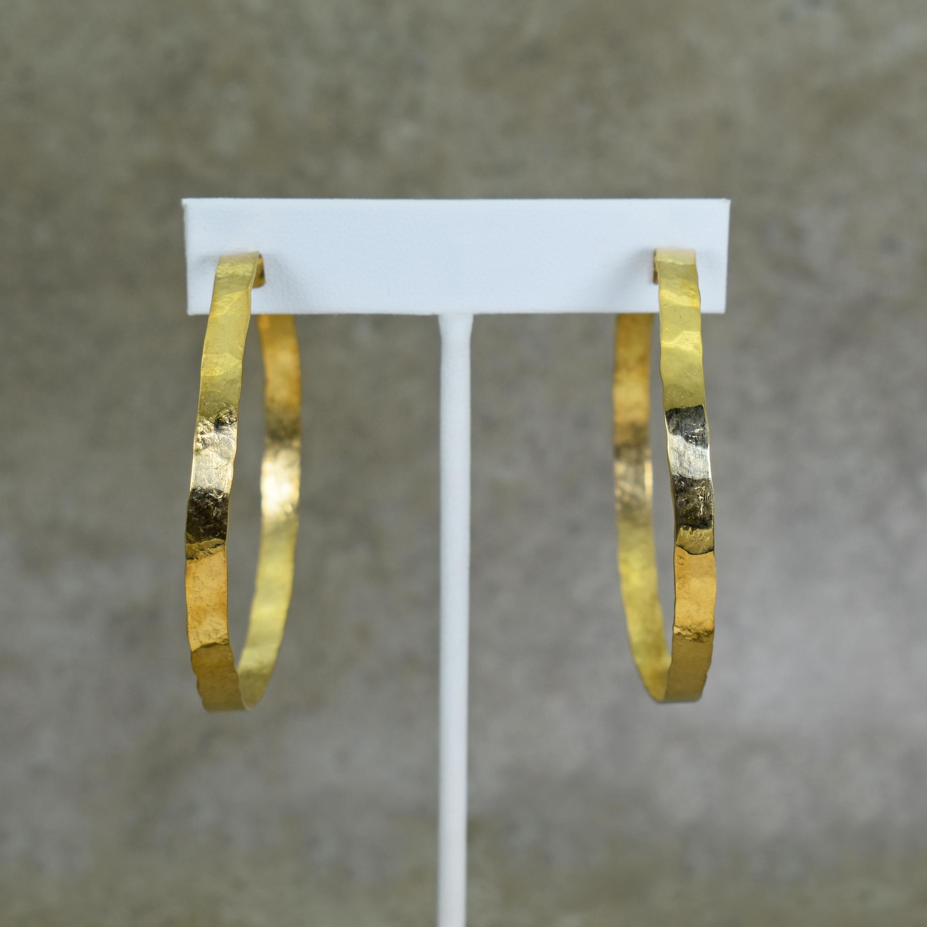 Large, solid 18k yellow gold hoop earrings. Each hoop is hand-forged and finished with a hammered, rustic texture. Earrings are 2.25