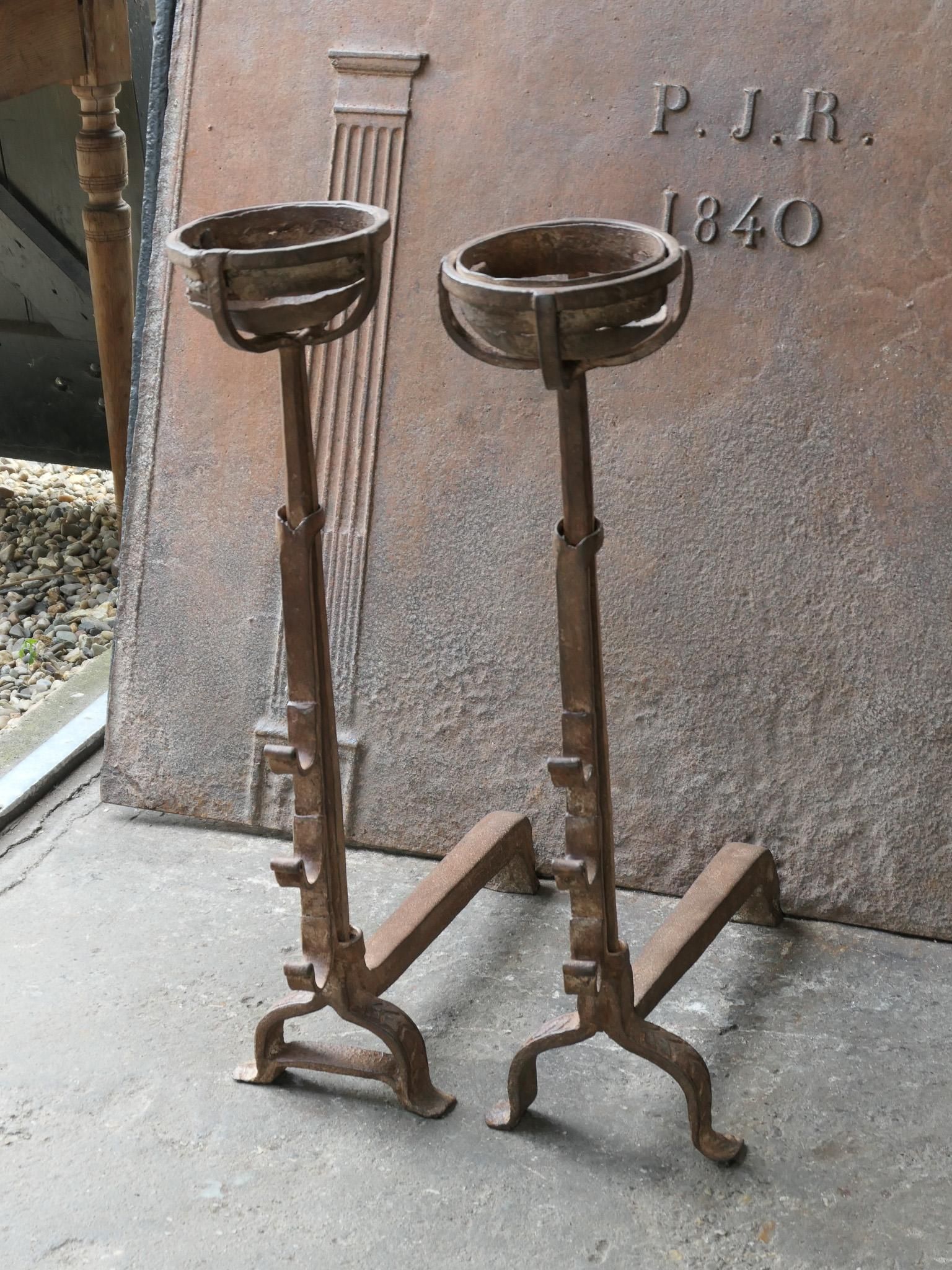 17th Century French Gothic Period andirons made of hand forged wrought iron. With cups to keep drinks or soup warm.  Also with spit hooks at different heights for grilling food. The andirons are in a good condition and fit for use in the fireplace.

