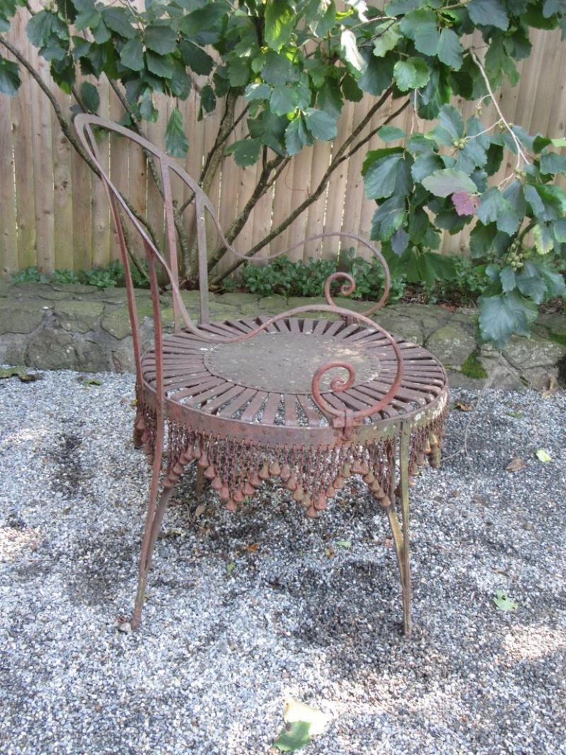 Questa coppia di poltrone da giardino in ferro forgiato a mano, proveniente dalla Francia della metà del XX secolo, mostra un'eleganza senza tempo. Le sedie  presentano una patina pesante che aggiunge carattere e autenticità. Le caratteristiche
