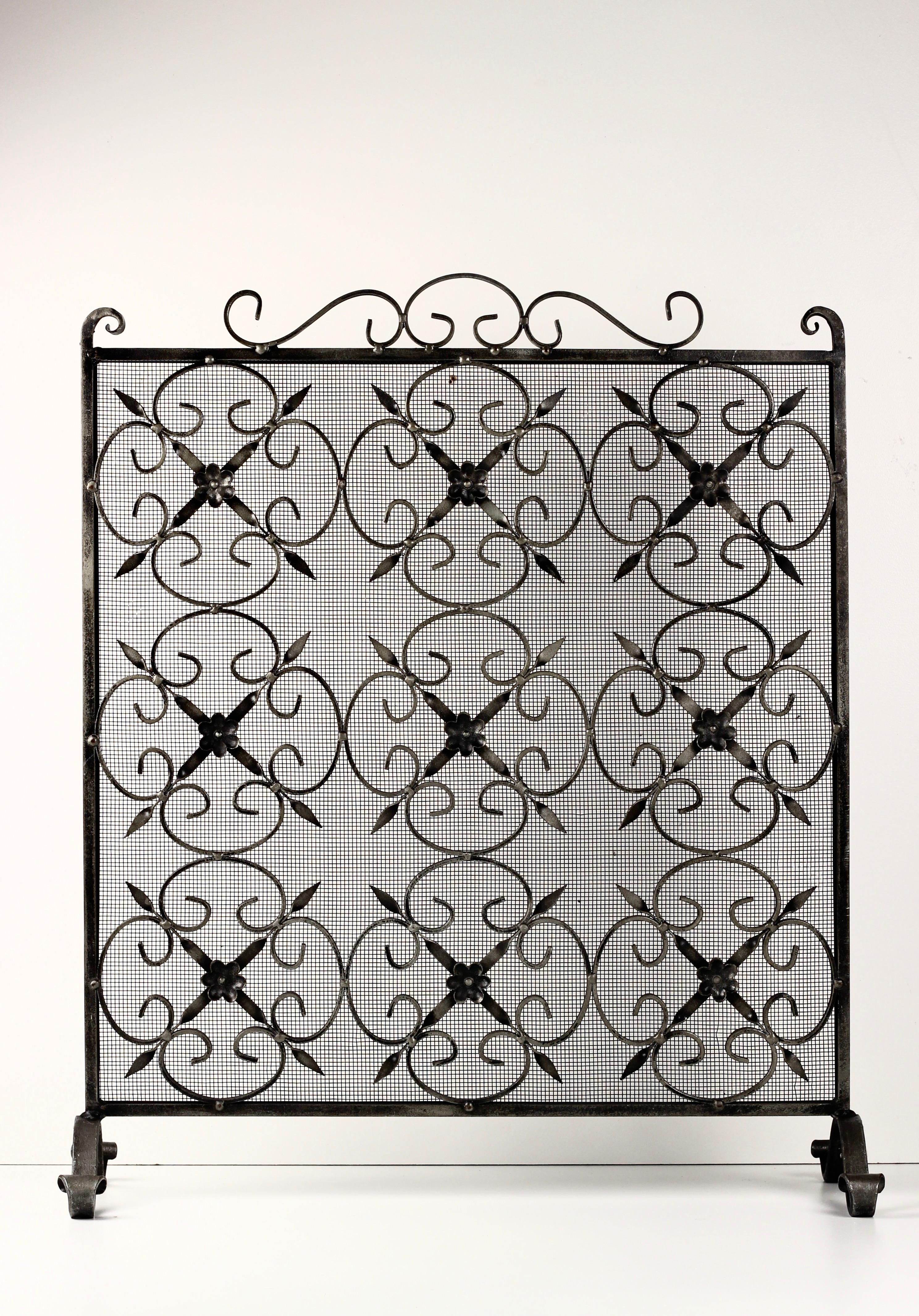 Discover the exquisite craftsmanship of our late 19th-century hand-forged and fire-welded Victorian Gothic Revival fire screen. This stunning piece features intricate scrollwork and stylized symmetrical fleur-de-lis motifs, each adorned with