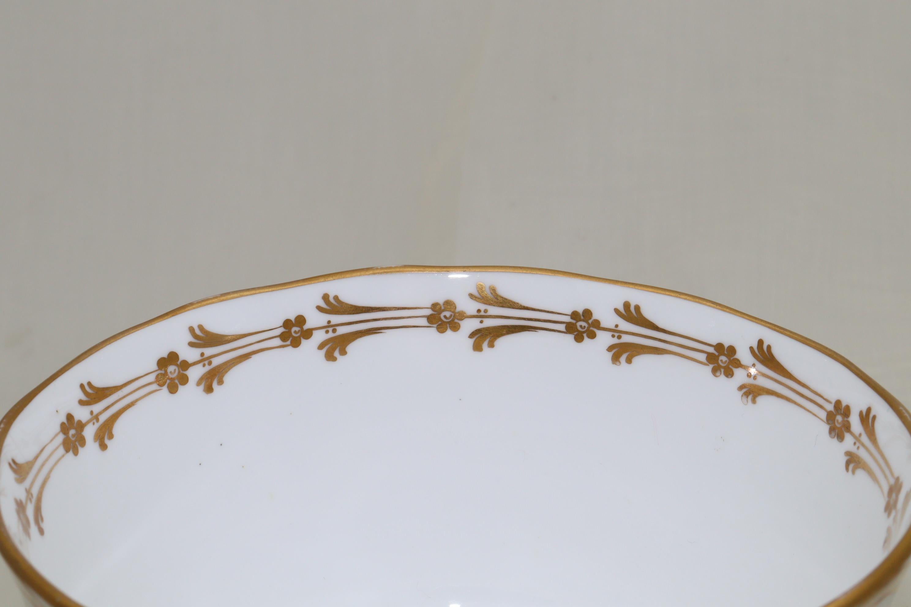 This Davenport porcelain slop bowl is decorated to the outside with a hand gilded pattern that features swags of flowers cascading from two intertwined ribbons that run around the rim. The inner rim carries a band of stylised flowers and there is an