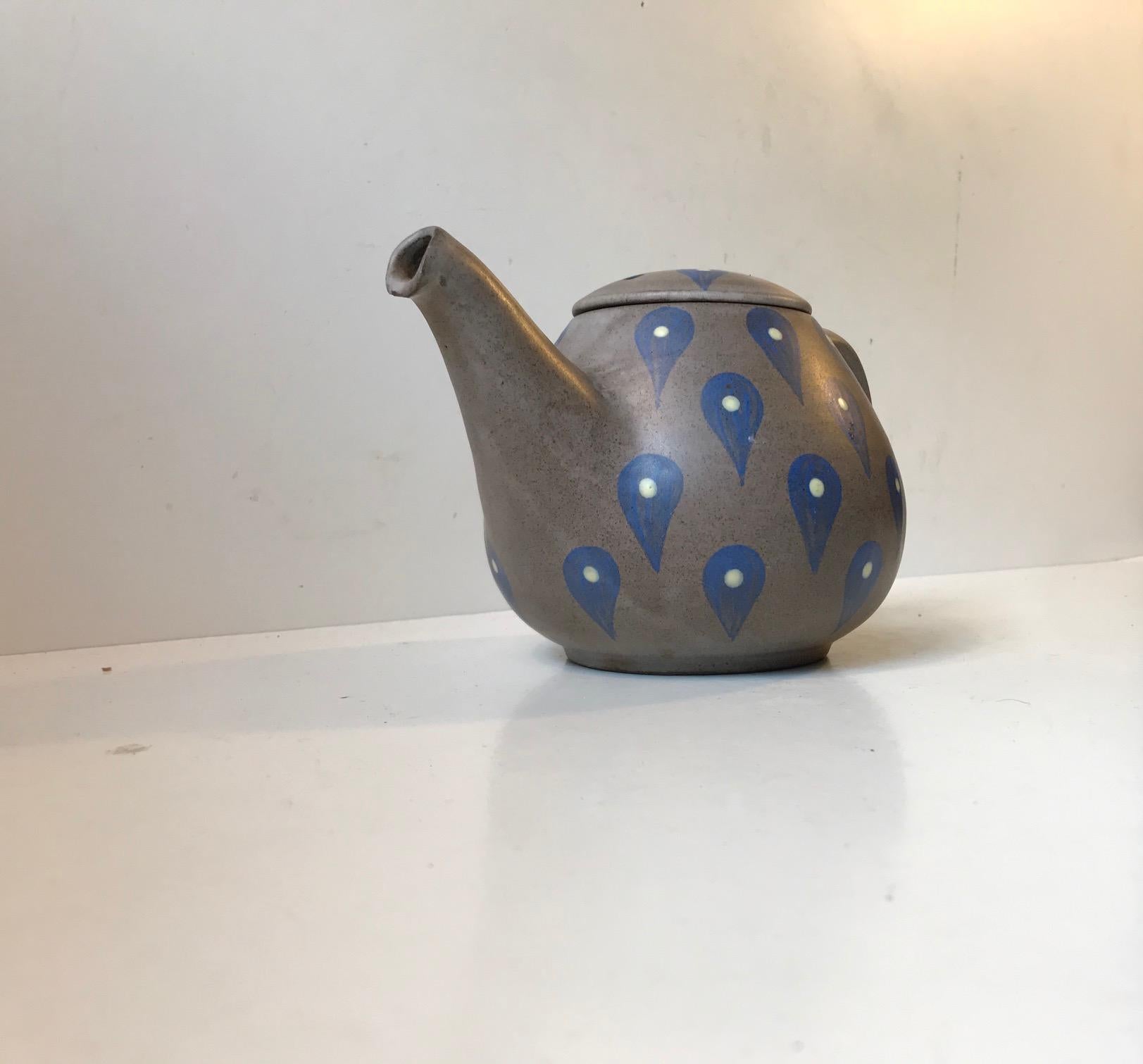 A Danish teapot decorated with hand applied blue and yellow drops on a dusty grey main-glaze. Designed and manufactured by Melle Keramik in Denmark during the 1960s. The colors and decor are unique to this studio piece. Its hand signed by the