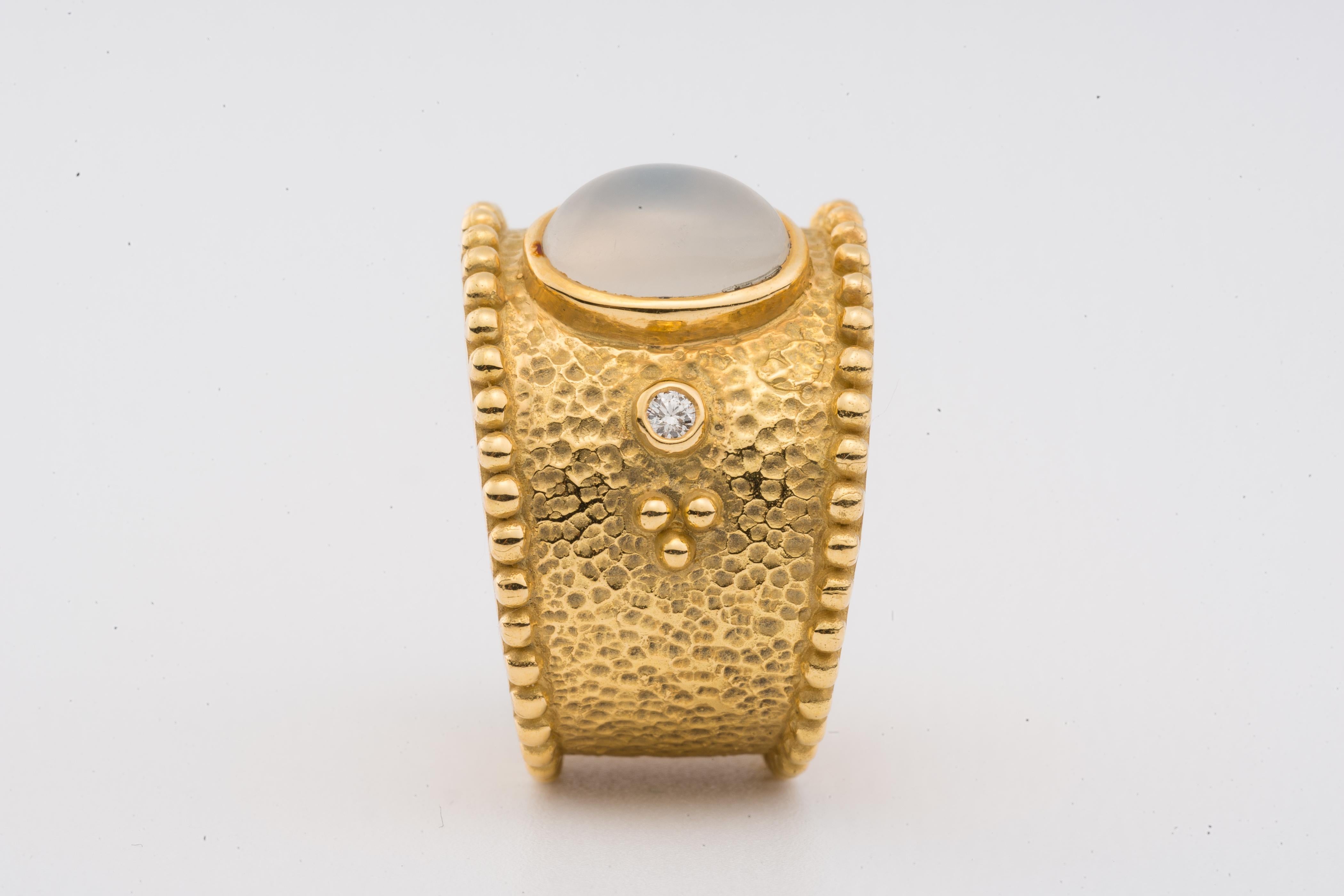 A hand-crafted 18K gold ring with an oval cabochon moonstone gem flanked by small  diamonds on the hand-hammered gold band, decorated with beaded edges.  

American ring size: 6 (Inside diameter: 16.6mm)

Designed by AMANDA CLARK for Altfield, our